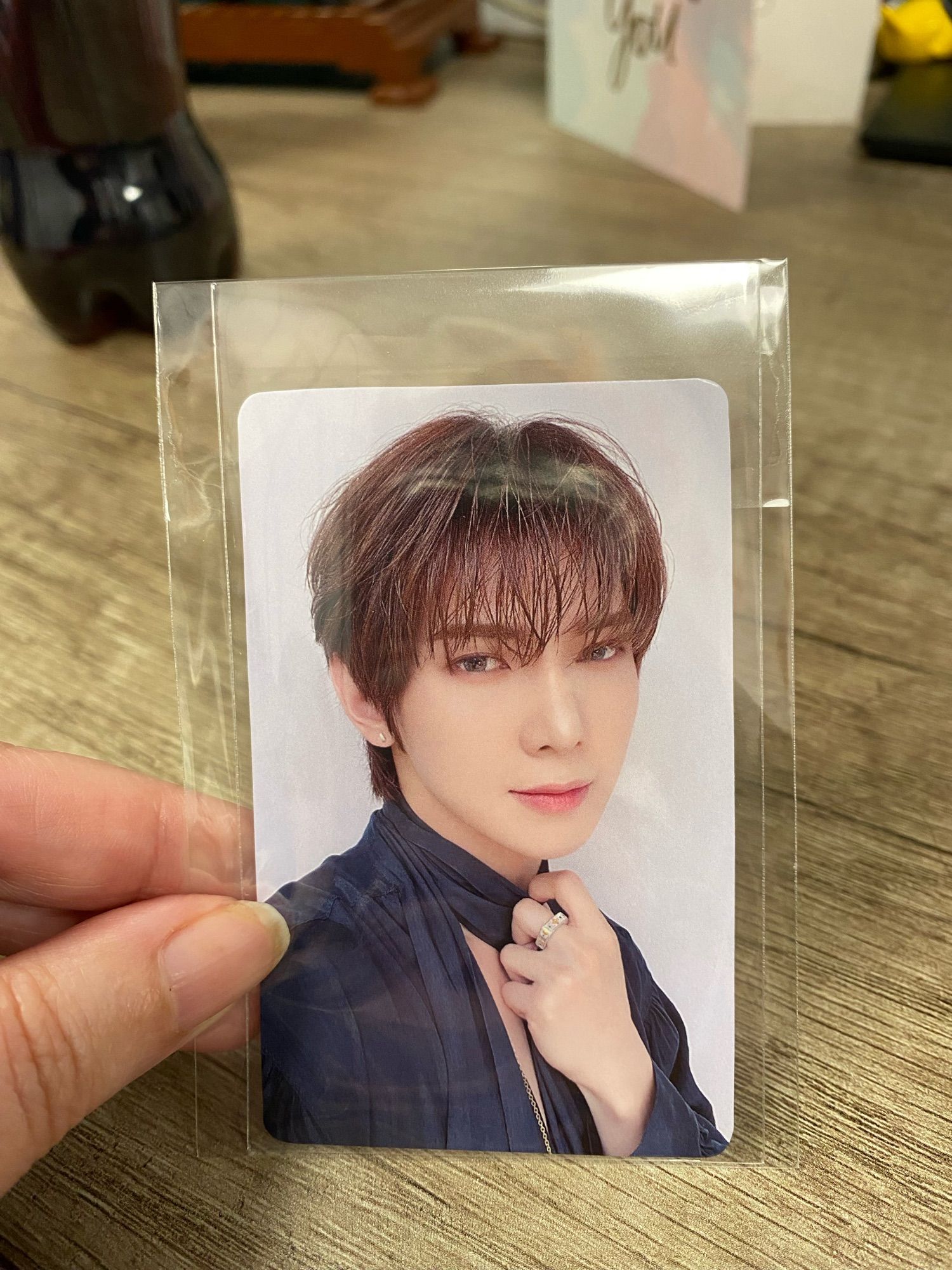 A Yeosang photocard where he is tugging on a scarf around his neck