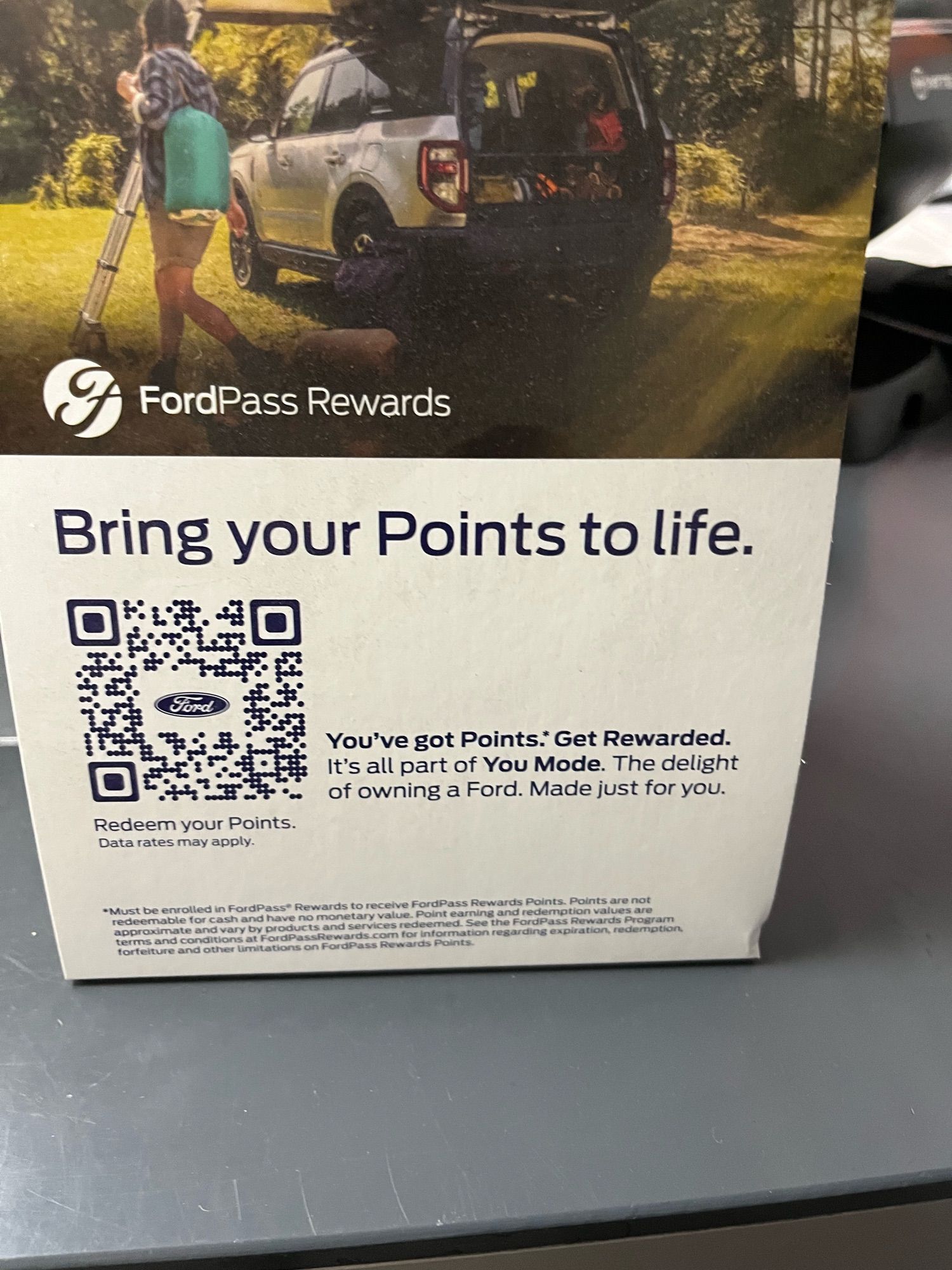 Ad card stood on a counter at a ford dealership. Text reads: “Bring your Points to life.
You've got Points: Get Rewarded.
It's all part of You Mode. The delight of owning a Ford. Made just for you.”