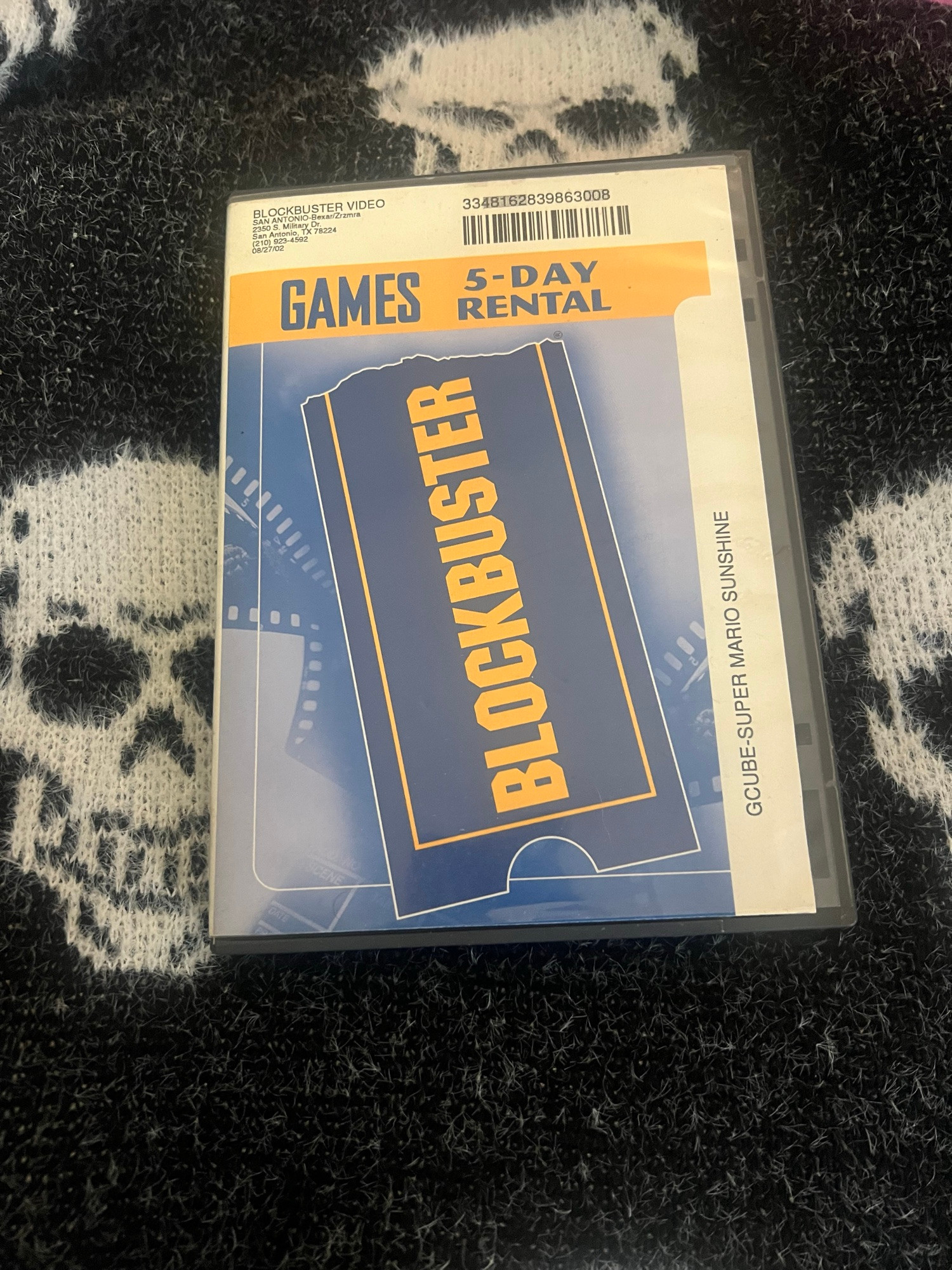A blockbuster game rental case on my skull blanket 
The date on it is 08/27/02



5-DAY RENTAL
BLOCKBUSTER
GCUBE-SUPER MARIO SUNSHINE