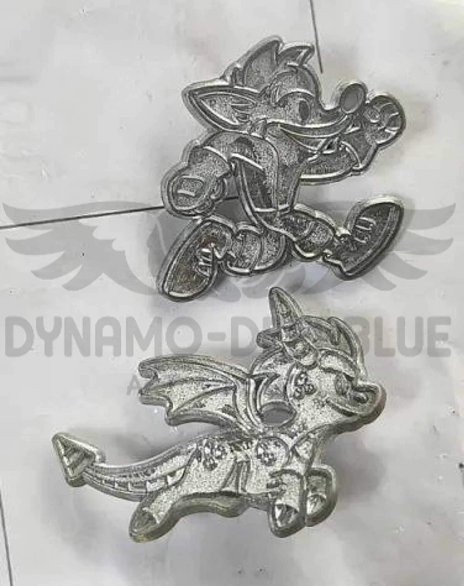 A photograph of two enamel pin metal molds, in the shape of Crash Bandicoot and Spyro the Dragon.