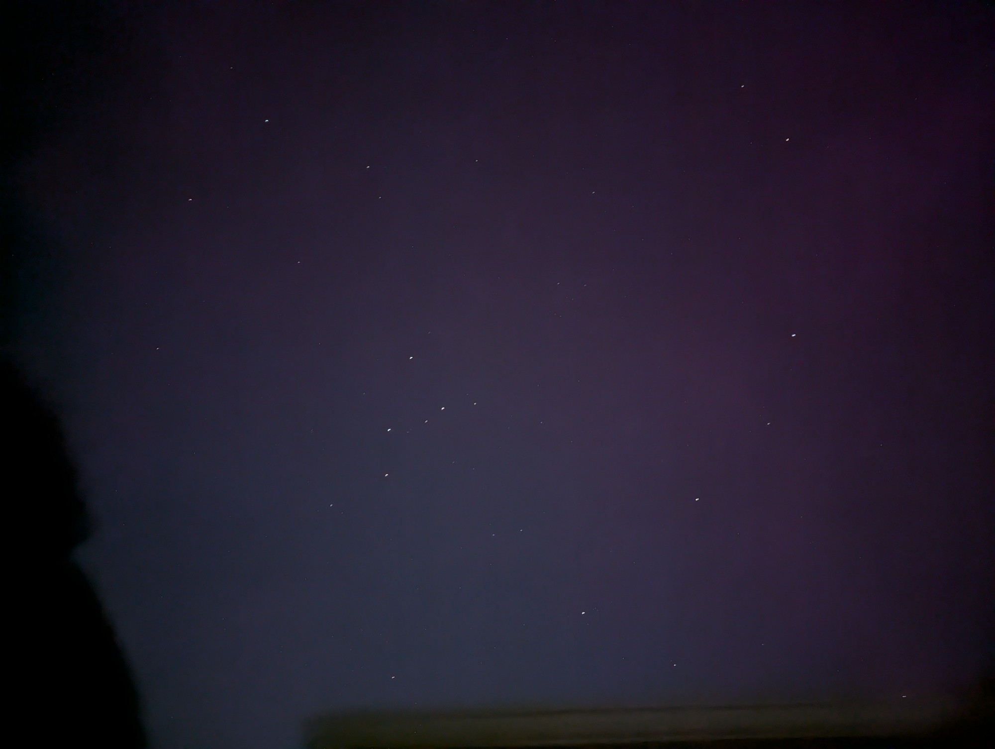 Constellation Cassiopeia and Andromeda against a slightly pink/purple tinge of Aurora in the sky