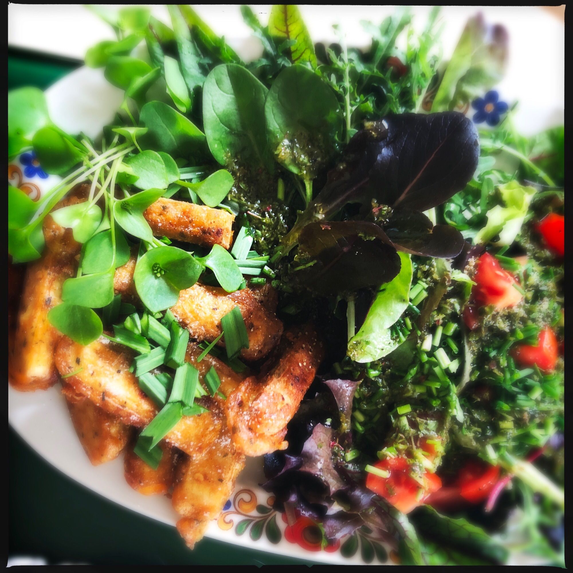 Eine Servierplatte voll mit buntem Kräutersalat. Blutampfer, Portulak, Rucola, roter Feldsalat, Zupfsalat, Babyspinat usw ein paar Tomatenwürfel, Schnittlauch. 

Daneben Tofusticks in gold angebratenem Teig