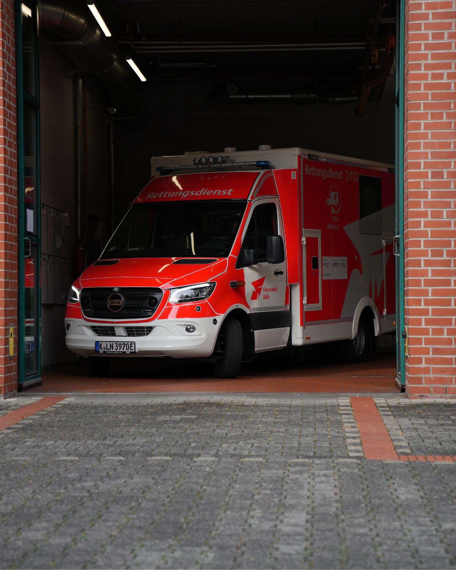 Auf dem Foto ist ein elektrisch angetriebener Rettungswagen zu sehen, der in einer Garage steht.