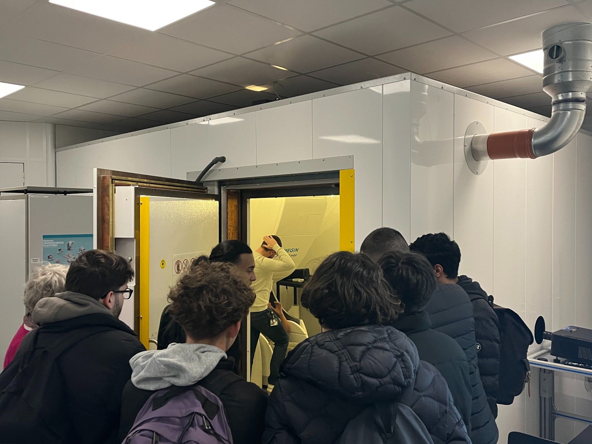 A group of students listening to an explanation of what an MEG scanner is