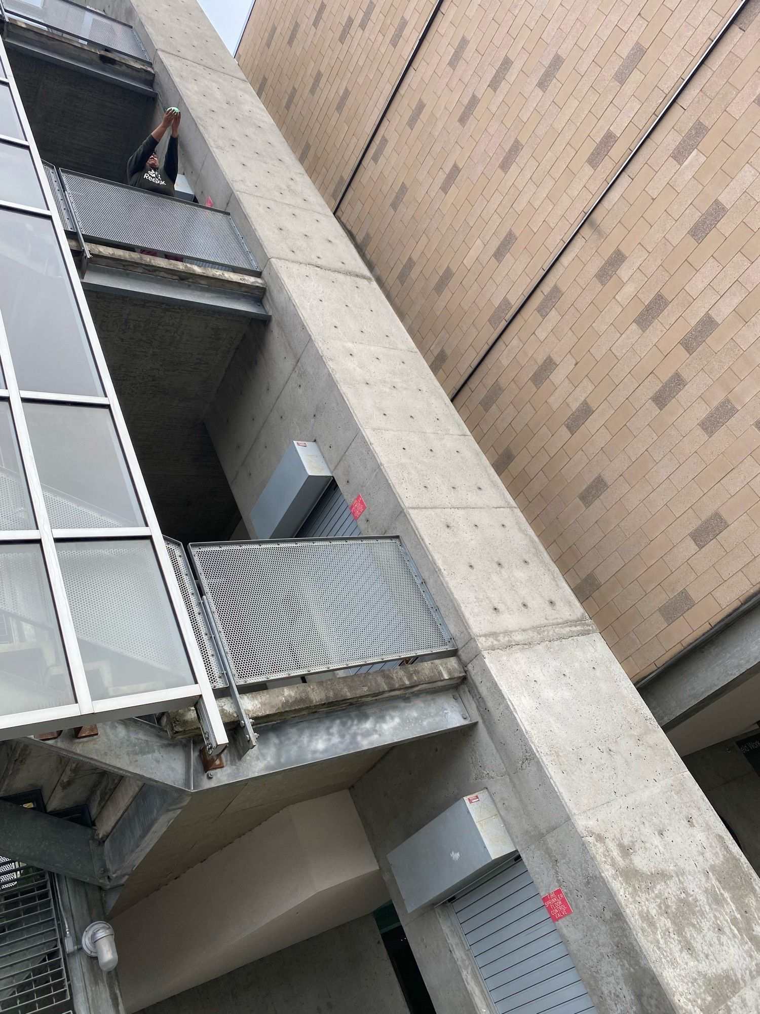 a student holding a water balloon off a balcony