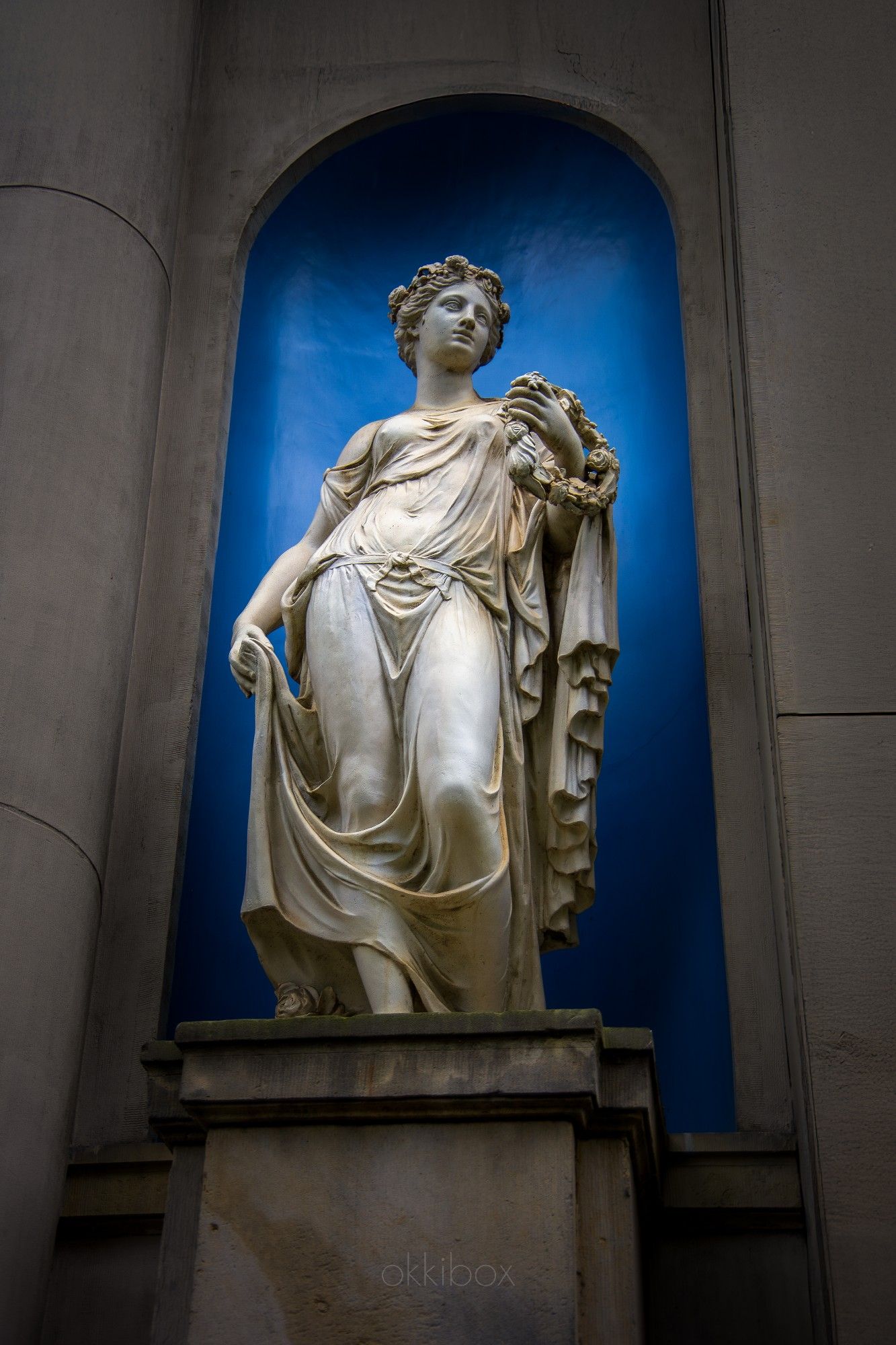 Aan de gevel van het koetshuis bij Museum Van Loon staat  de sierlijke godin Flora op haar sokkel in een blauwe nis

Het koetshuis van Museum Van Loon te Amsterdam werd in de zeventiende eeuw ontworpen door Adriaan Dortsman, die ook tekende voor het hoofdgebouw. In  1774-1775 werd het koetshuis ingrijpend vernieuwd door Coenraad Sander en kreeg het gebouw het uiterlijk dat het ook vandaag nog heeft.

