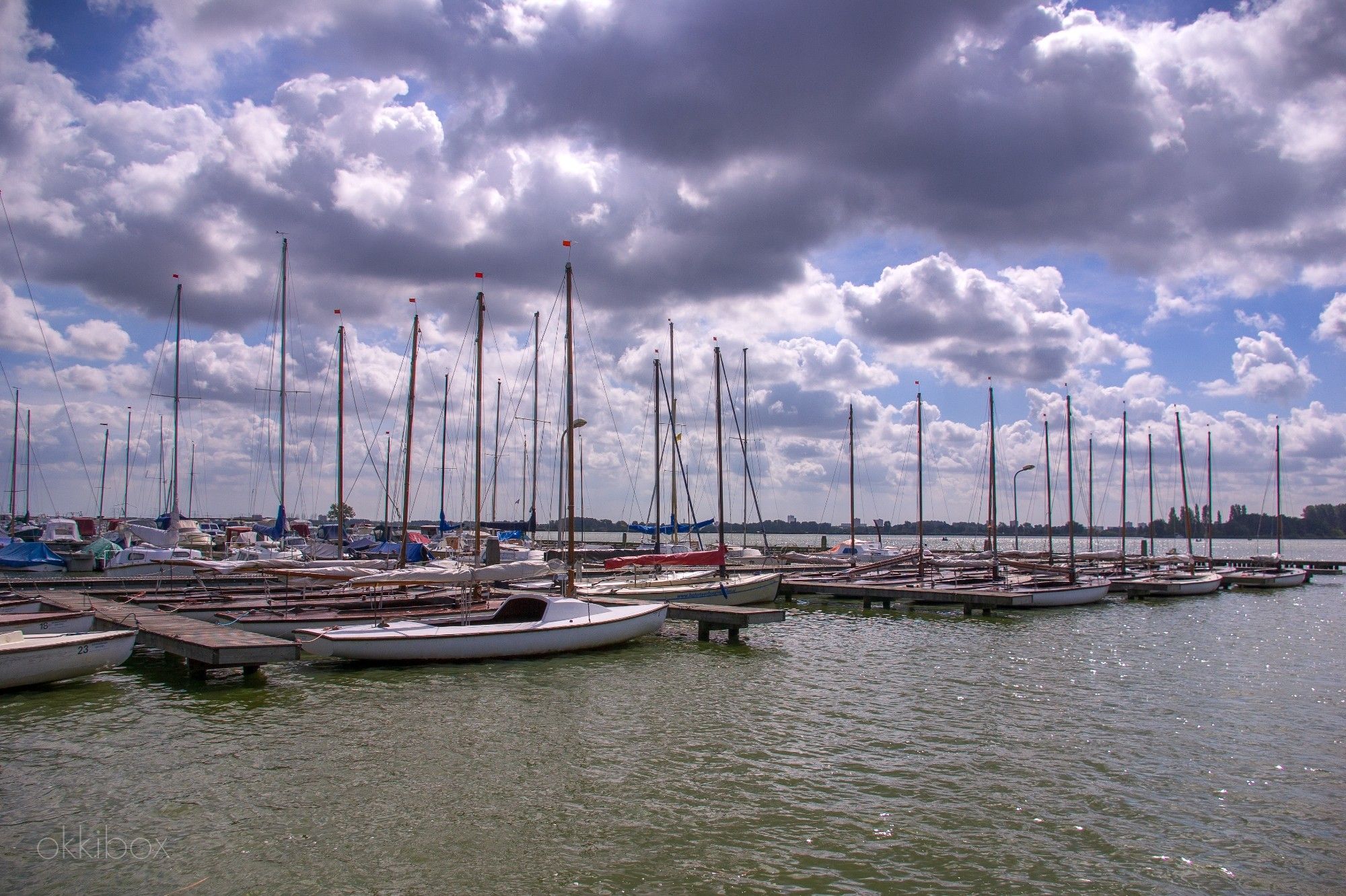 Een kleine haven vol zeilboten bij de Rottemeren met een imposante wolkenlucht.