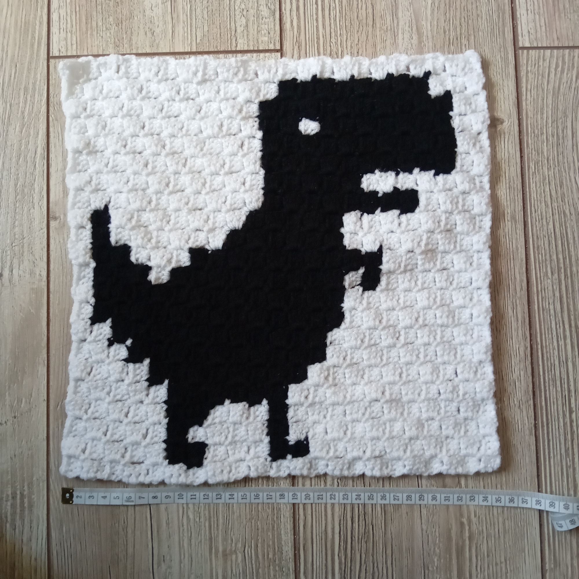 Projet au crochet : le dinosaure de chrome quand on a plus internet en noir sur fond blanc avec un effet pixel art. Un mètre en bas indique qu'il fait 35 cm de large.