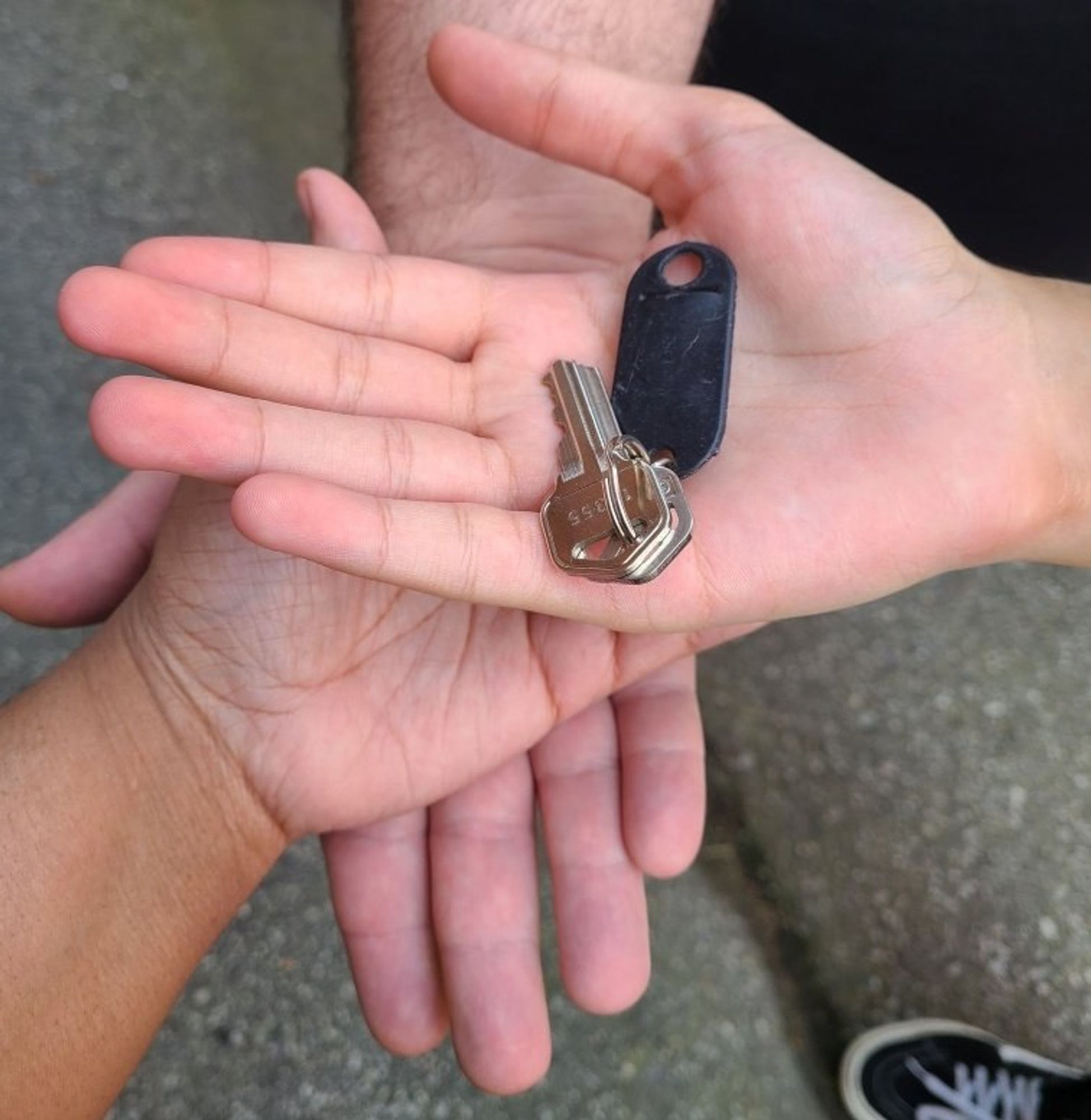 A picture of Tiffany, Malus and their son hand stacked on top of each other. With their son hand on top and Malus on the bottom. I the son hand is the keys to their new place.