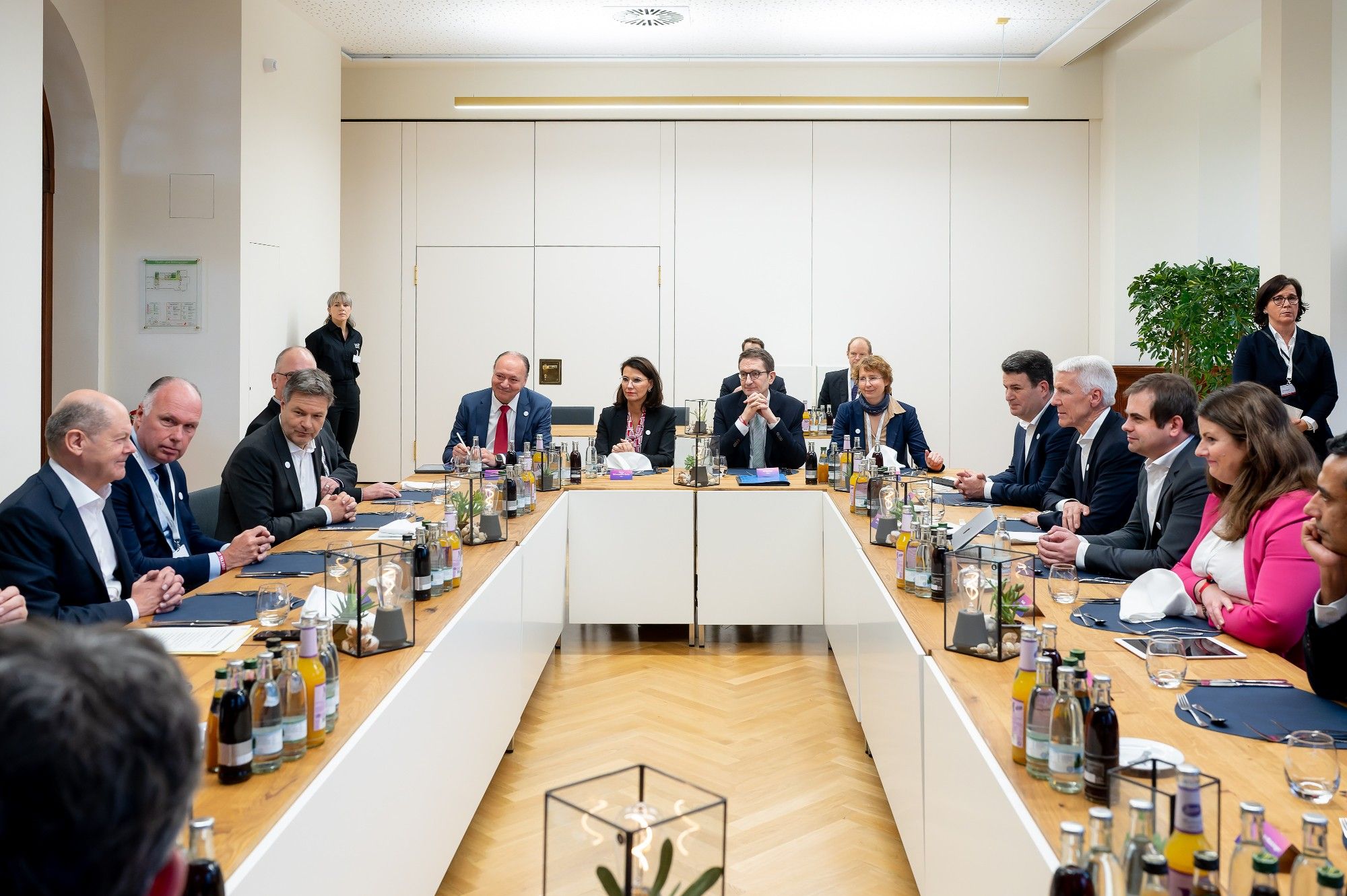 Verschiedene Personen sitzen um eine O-förmig angerichtete Tisch-Tafel. Darunter Bundeskanzler Olaf Scholz, Robert Habeck, Marc Reinhardt, Ann Cathrin Riedel und viele mehr. (Foto: BMWK/Christian Kruppa)