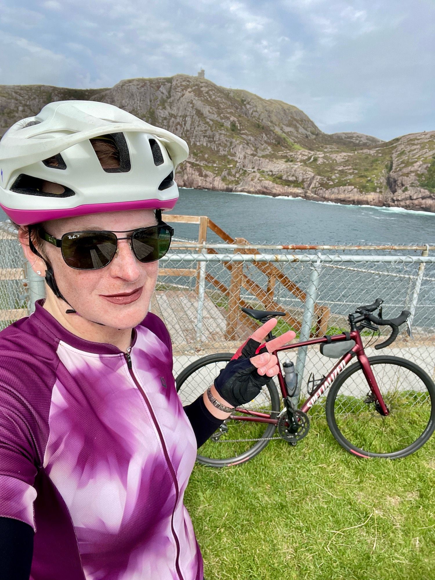 Cailín is standing at the end of the trail at Fort Amherst. Behind her is Cabot Tower on top of Signal Hill, the narrows leading into St. John’s harbour, and her bike.