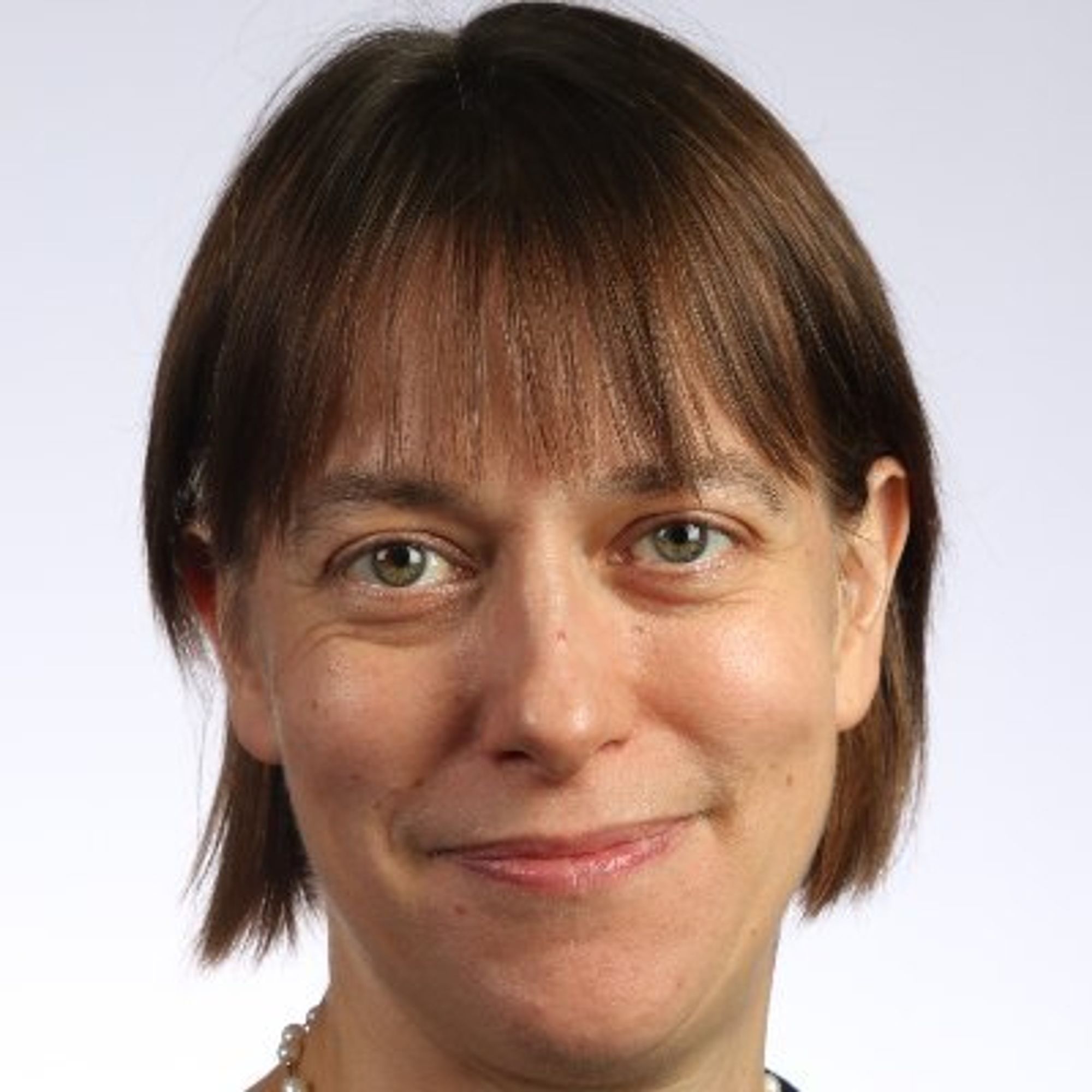 Color photo portrait of Pauline Barmby, a fair-skinned woman with red-brown hair worn in a chin-length bob with bangs. She looks into the camera and smiles. She looks very professional.