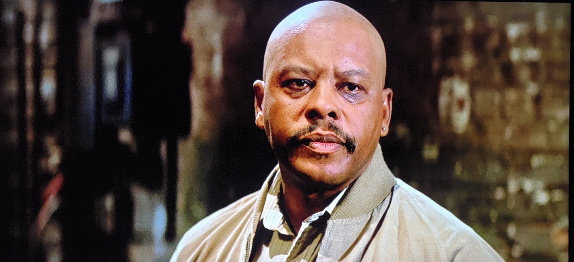 A photo from the movie of a bald black man with a mustache. From the movie They Live 