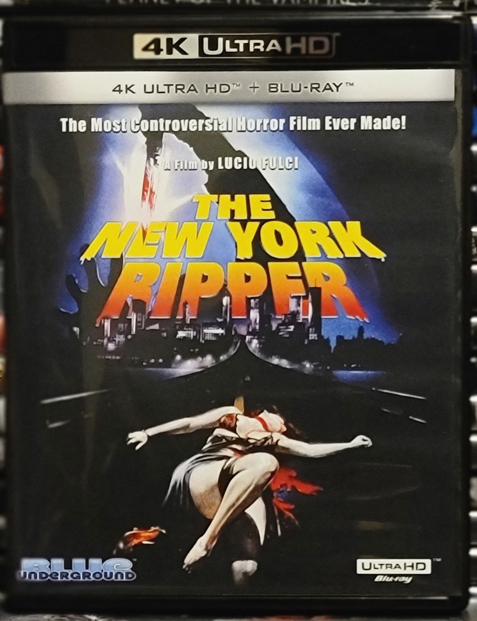 Blu ray cover for New York Ripper. The image shows an arm with knife wielding hand held above the New York cityscape. Below is a dead woman.