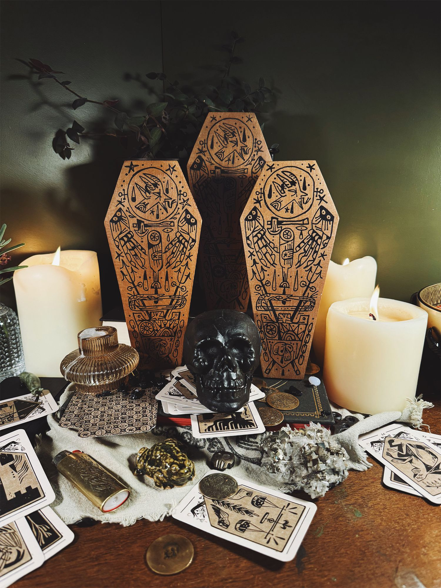 three painted wood coffin plants with devilish imagery drawn on them in a pile of occult themed stuff