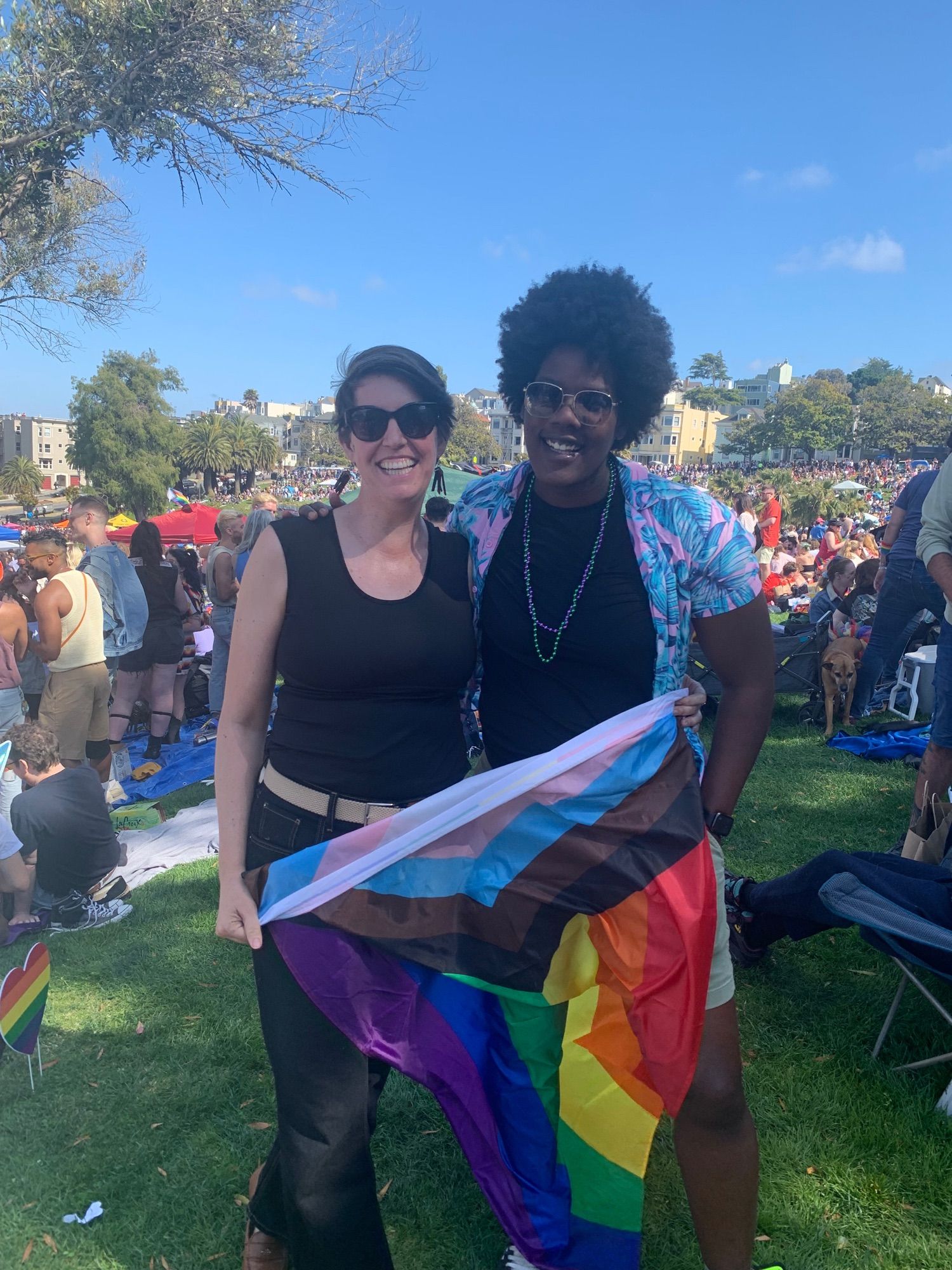 Cynthia and Racine at Dolores Park for Dyke March, holding a progress pride flag.