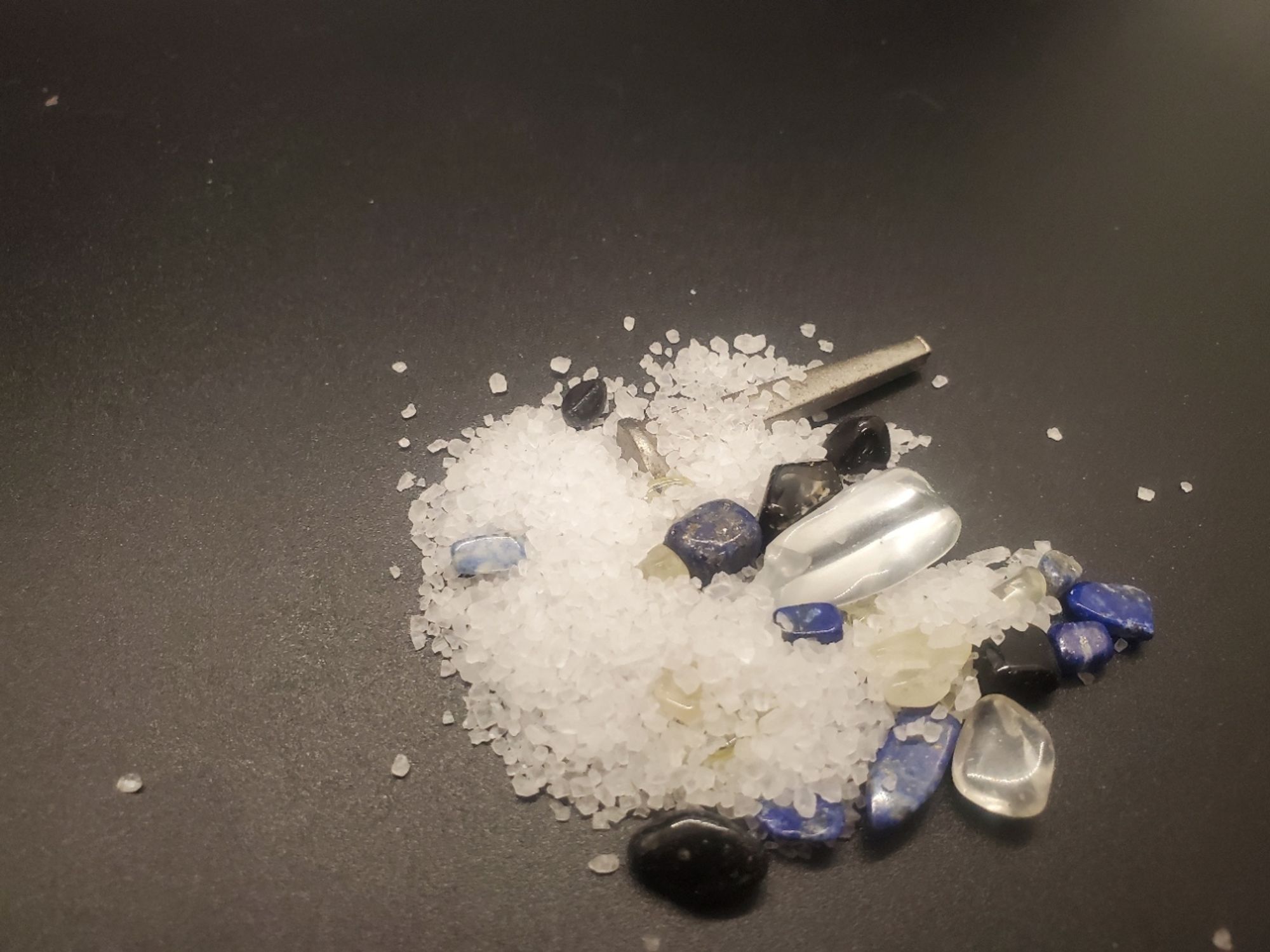 A pile of salt, Citrine, Clear Quartz, Obsidian, Lapis Lazuli, and an Iron nail.