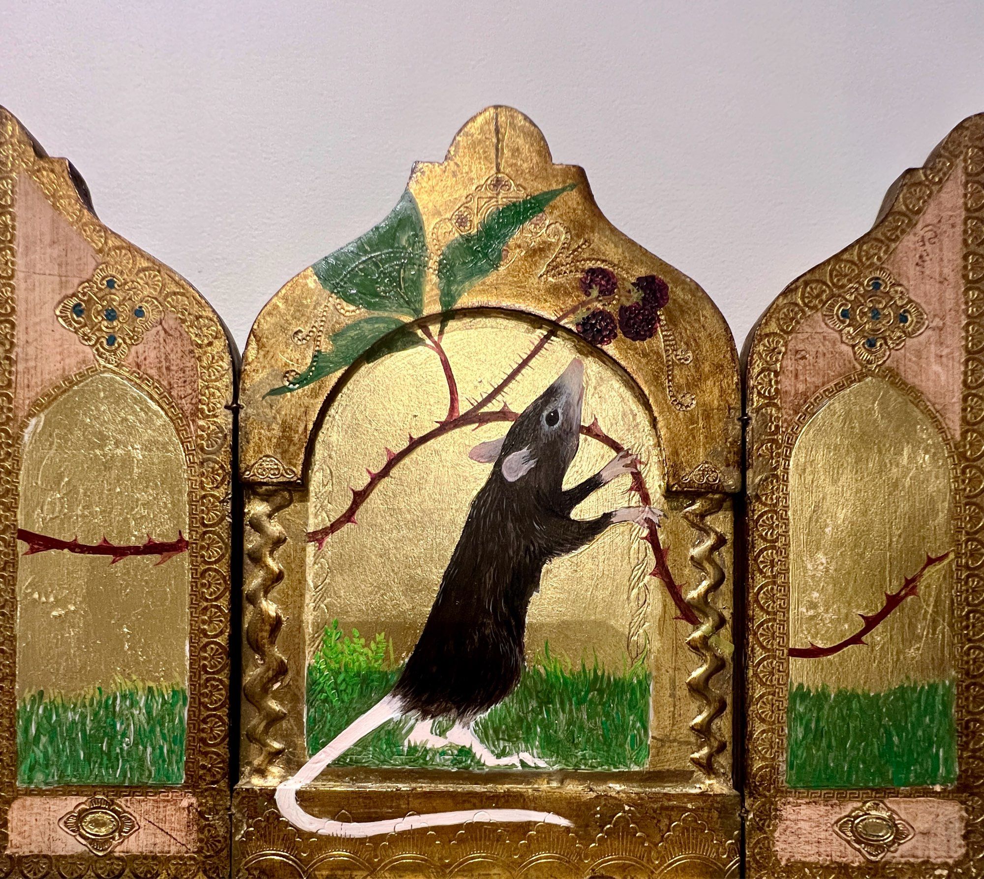 A rat stands on it’s hind legs and stretches up to sniff brambles painted on gold leaf laid on vintage Italian gilt wood folding panels