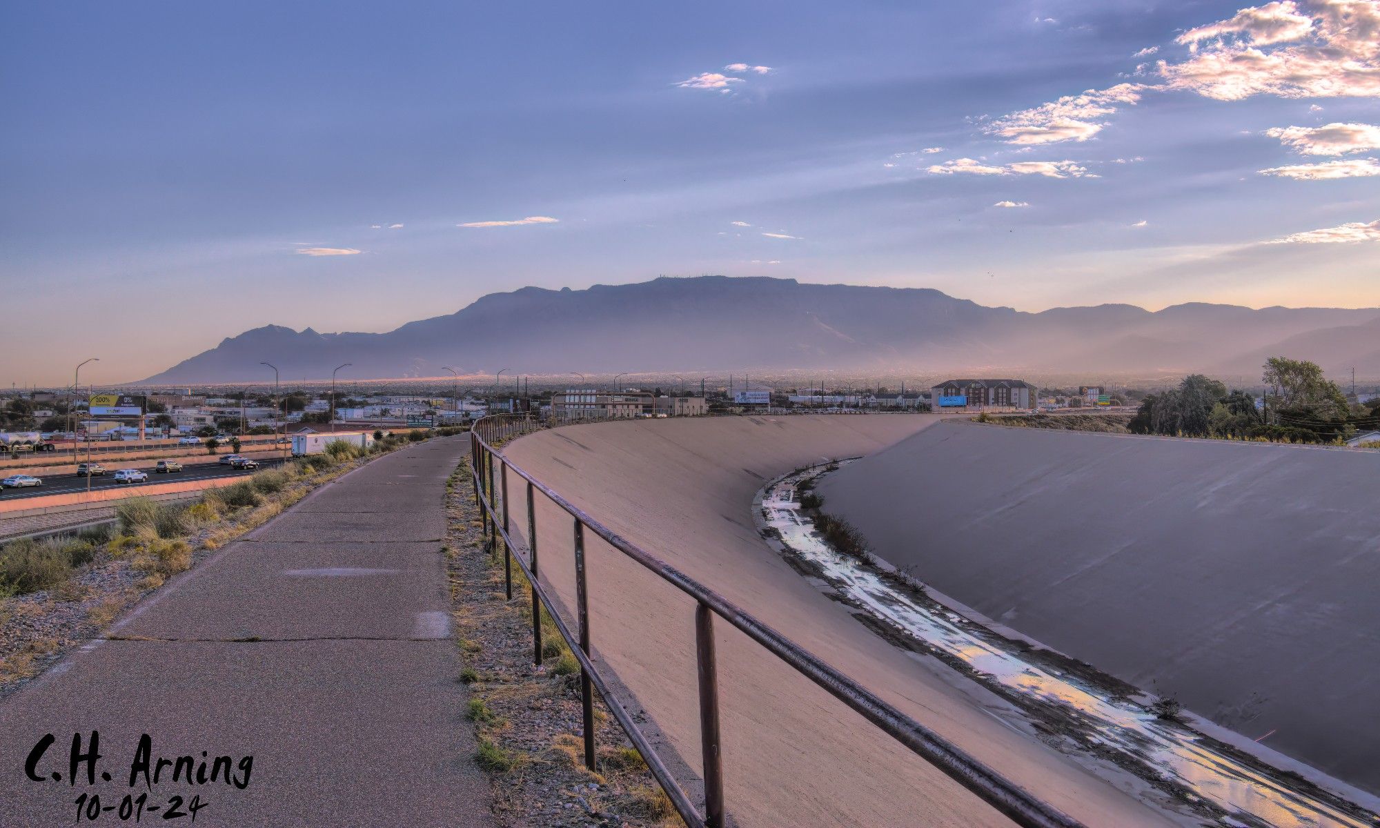 This morning, I took the North Channel Trail in the opposite direction, and it rewarded me with a stunning view of the Sandia Mountains as the sun began to rise. My 10/01/24 postcard captures that moment, taken from the trail just north of UNM, as it runs parallel to the freeway. The soft light bathed the dust in the air, creating a gentle glow on the mountain.