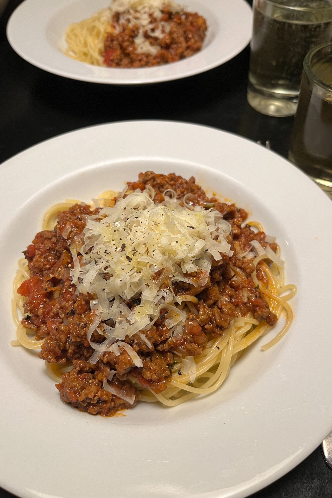 In zwei tiefen Tellern Spaghettini und Bolo, darüber Parmesan, Pfeffer und Olivenöl, dazu zwei kleine Glas Wein