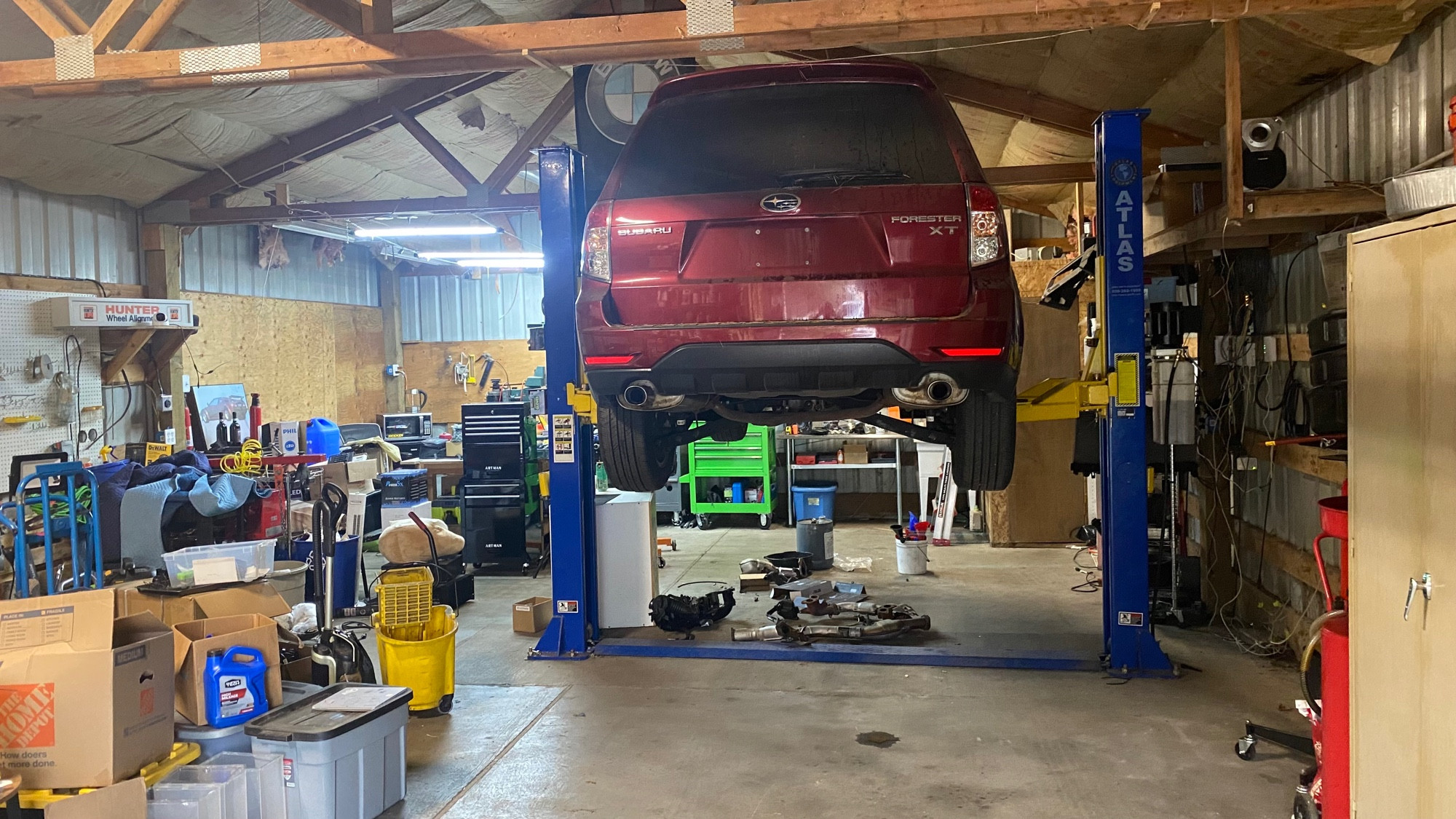 red car raised up on a car lift inside a good-sized garage bay