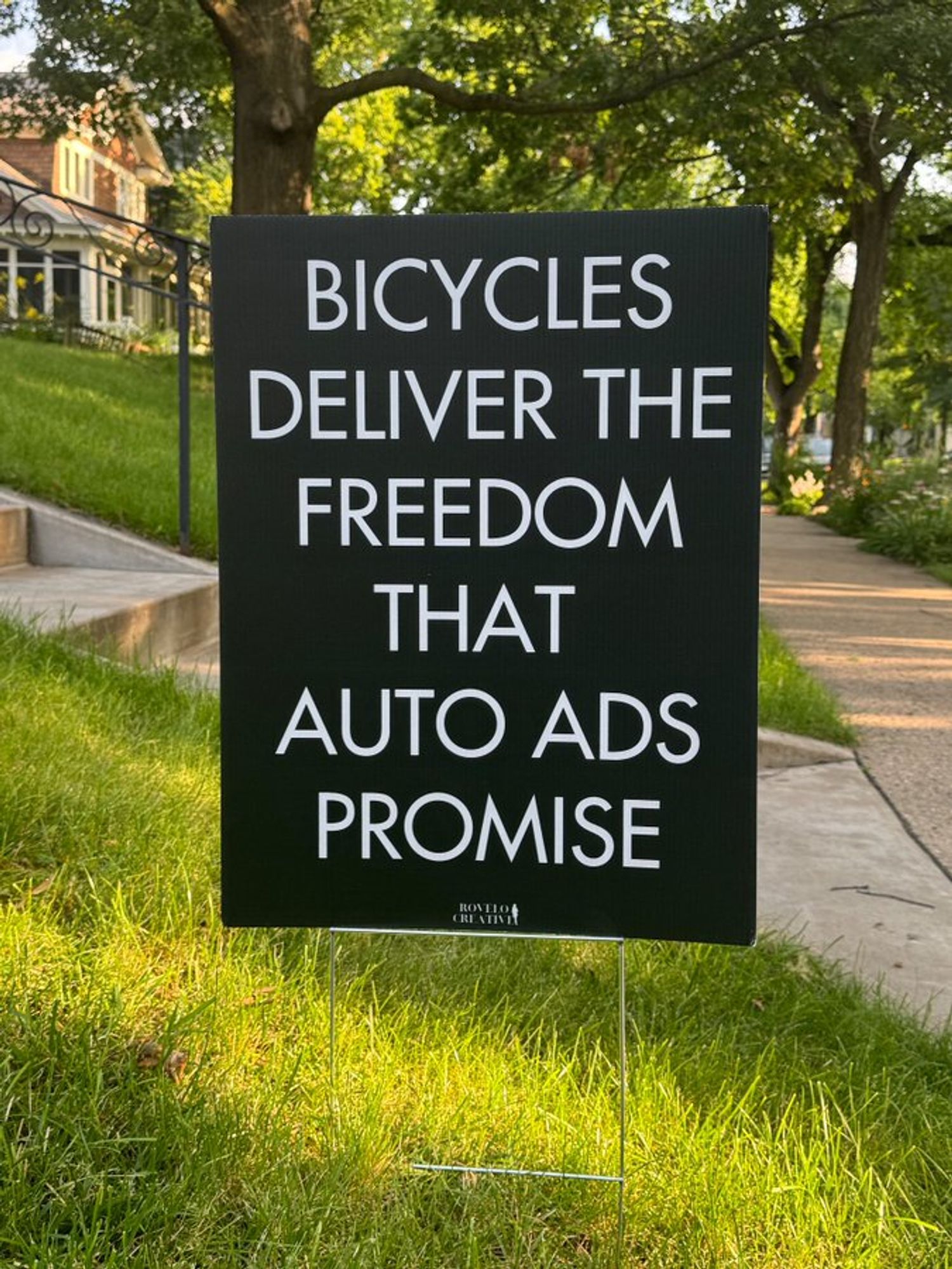 Black yard sign with white type Bicycles deliver the freedom that auto ads promise