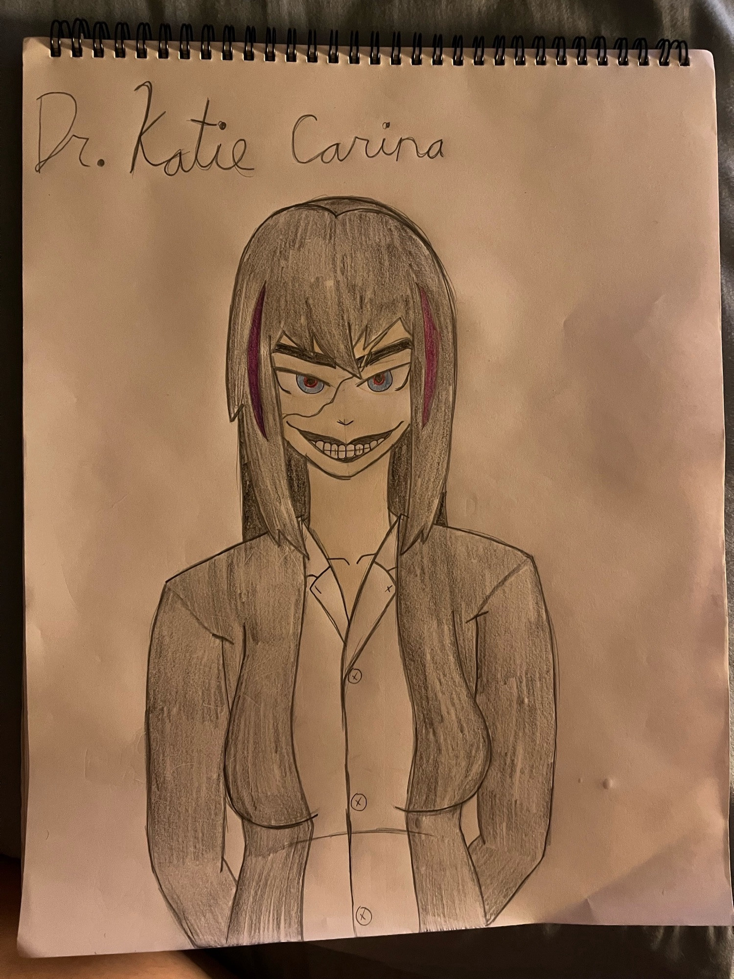 A drawn picture of one of my characters, Dr. Katie Carina, who wears a stark-white button-up shirt with a black coat, has black hair that's longer in the back, but with a shorter front, which has two strands of pink on either side, and has eyes that are blue on the outside but red on the inside, and a large scar going from beneath her right eye (our left) to the left side (our right) of her forehead, cutting through her left eyebrow. She's holding her head down while looking to the front, right at you, with a creepy smile on her face; an expression that I, the artist, am really proud of accomplishing.