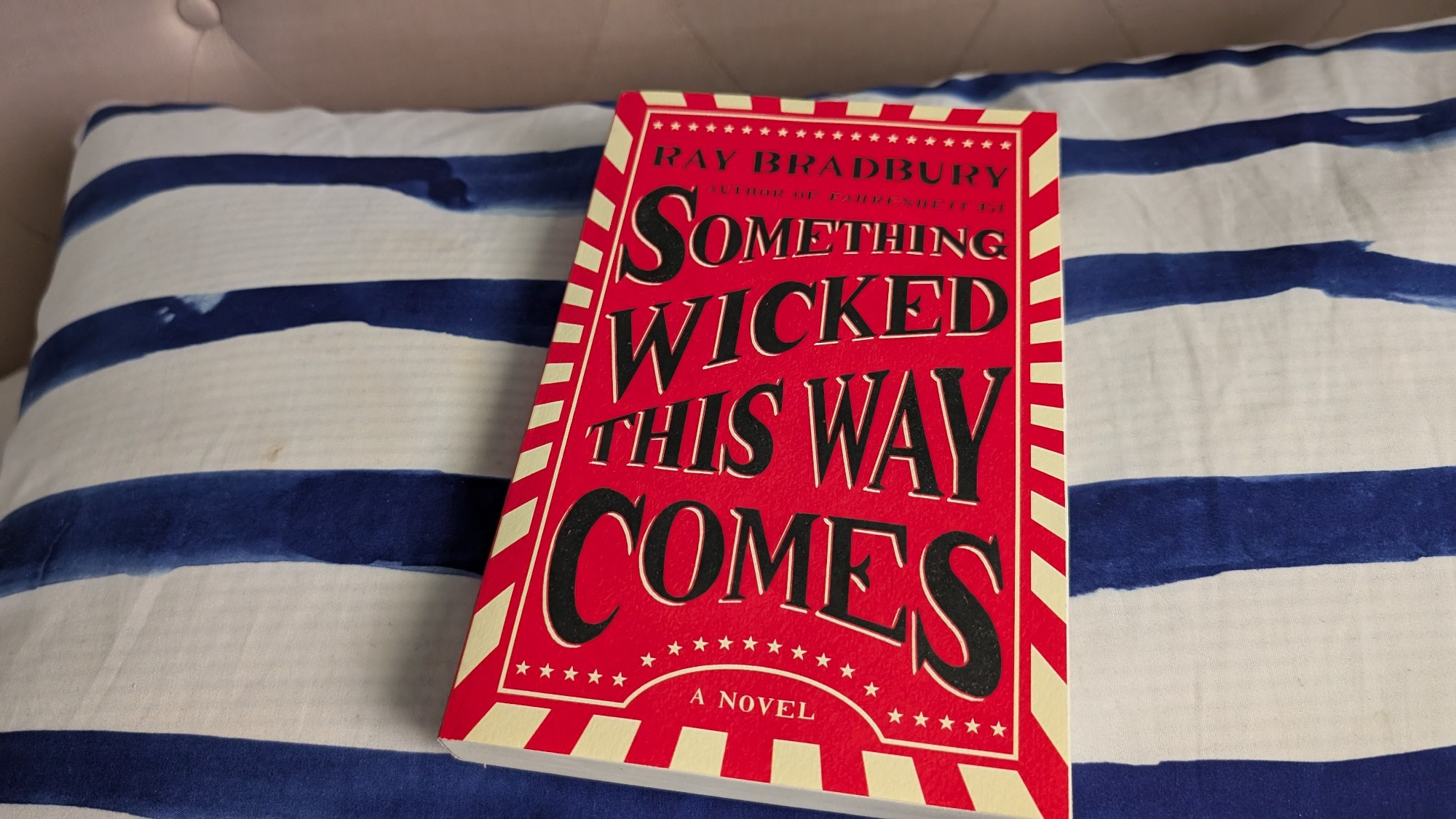 The cover is red. The edges have a very pale yellow pattern of angled rectangles, like a sun burst. Stars of the same colour sit in rows near the top and bottom. The title fills most of the cover in black text. There's a sort of carnival poster feel to the whole thing.