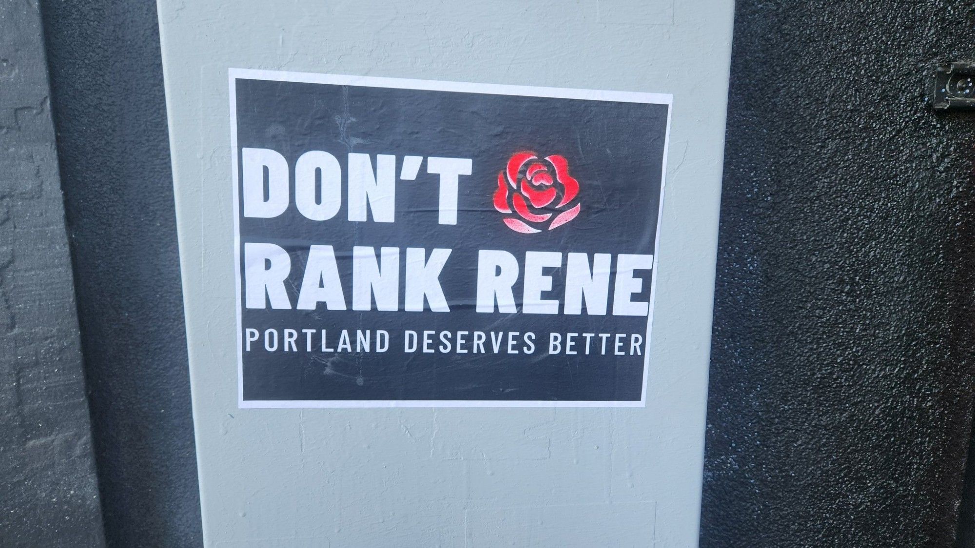 A black sticker with white text is adorned with a single red rose bloom reads: "Don't Rank Rene -- Portland Deserves Better".