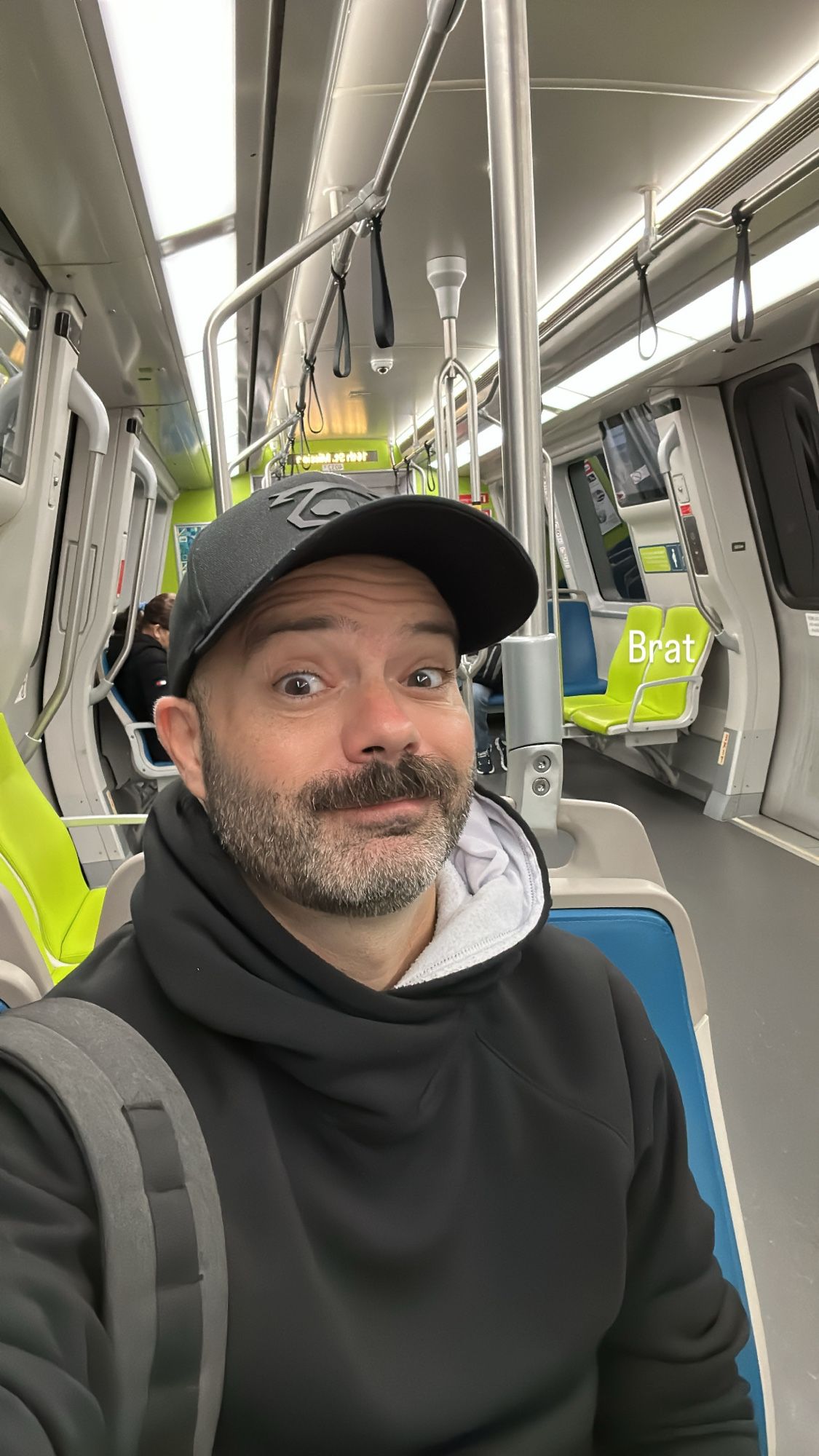 Me in a black hat and black hoodie on the bart train