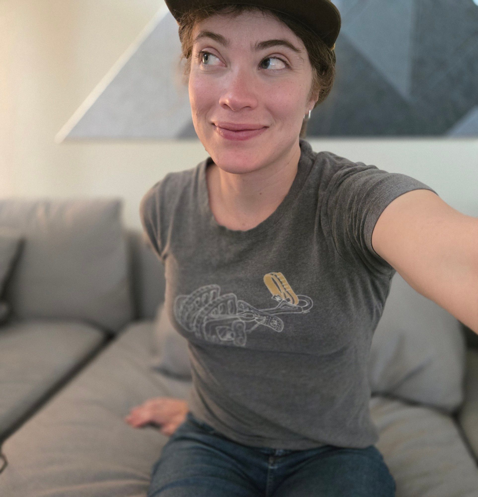 trans girl in jeans and a t shirt sitting on a couch