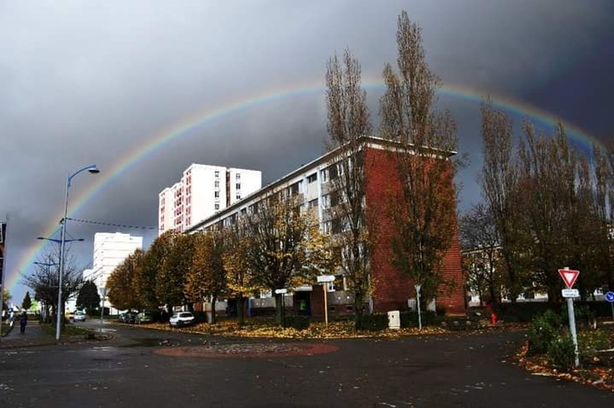 Photo prise il y a 13 ans, à Avion, dans le Pas-de-Calais, d'un arc-en-ciel complet au-dessus de barres d'immeubles HLM avec un ciel très gris.