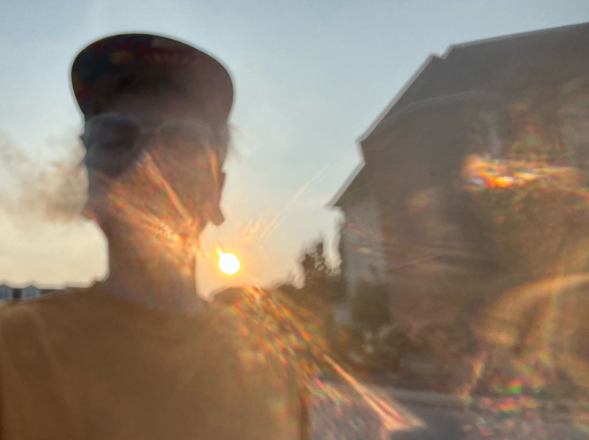 A double-vision blurry rendering of Jasper with the sun setting behind him and producing unevenly diffracted beams of intense rainbow light