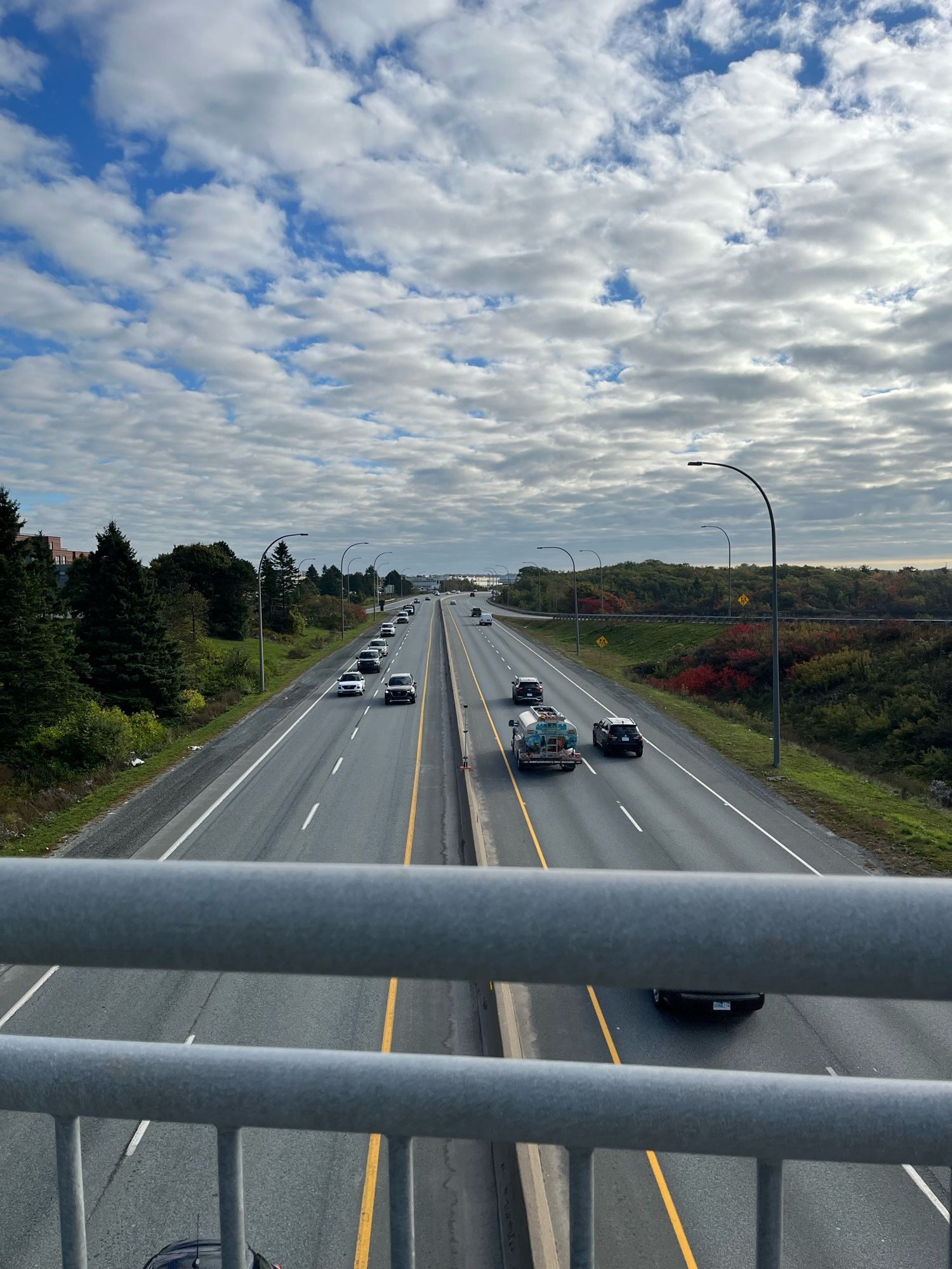 View from an active transportation bridge looking over a large highway. Some fall colours on trees in the background look nice, at least.