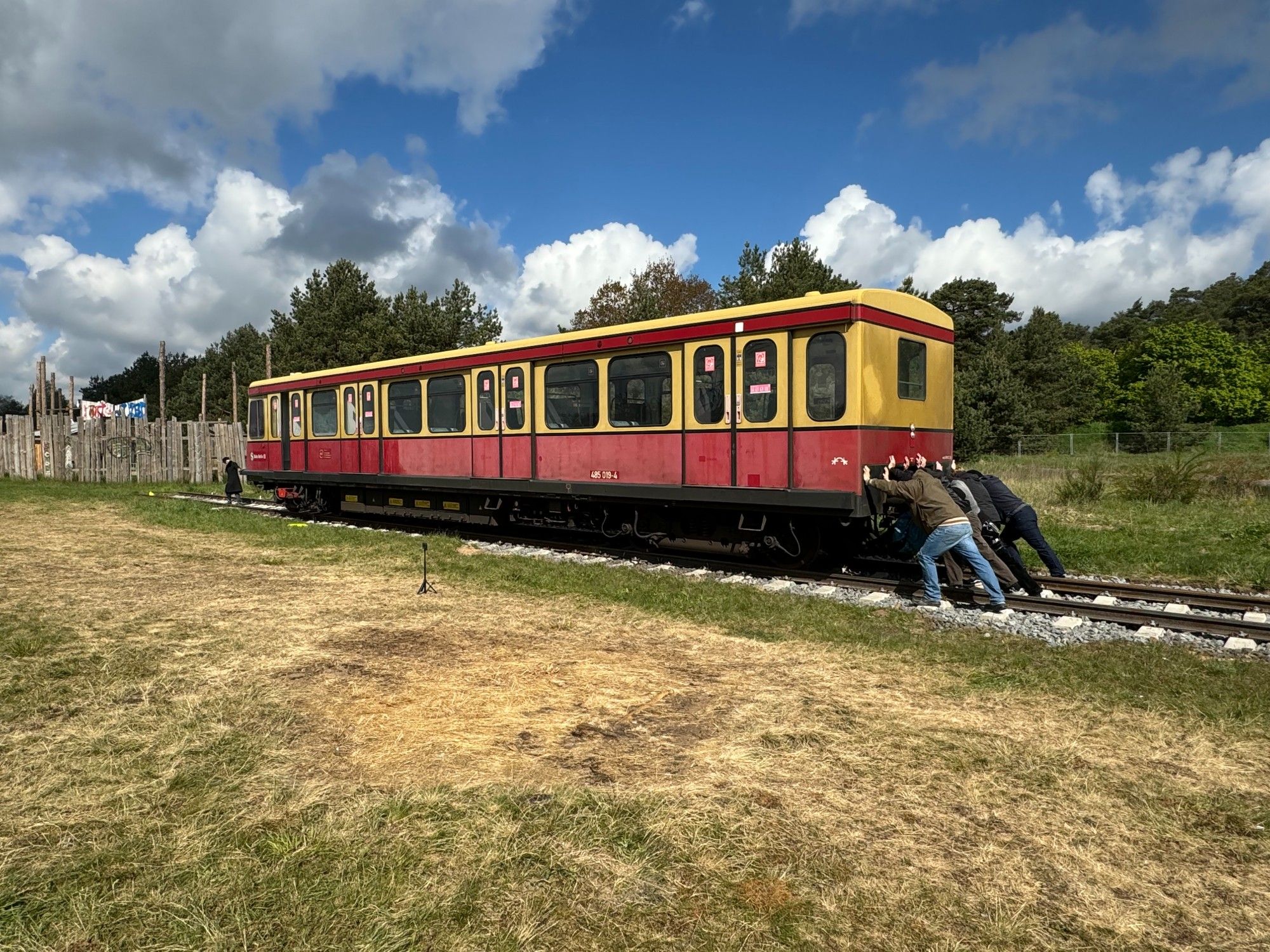 Die letzten Meter des Transports mussten mit Muskelkraft bewältigt werden. Eine Gruppe Menschen schiebt einen Triebwagen der Baureihe 485 auf ihre endgültiger Position auf die Gleisen auf dem Gelände des "Zurück zu den Wurzeln"-Festivals in Brandenburg. Foto: Jens Wiesner