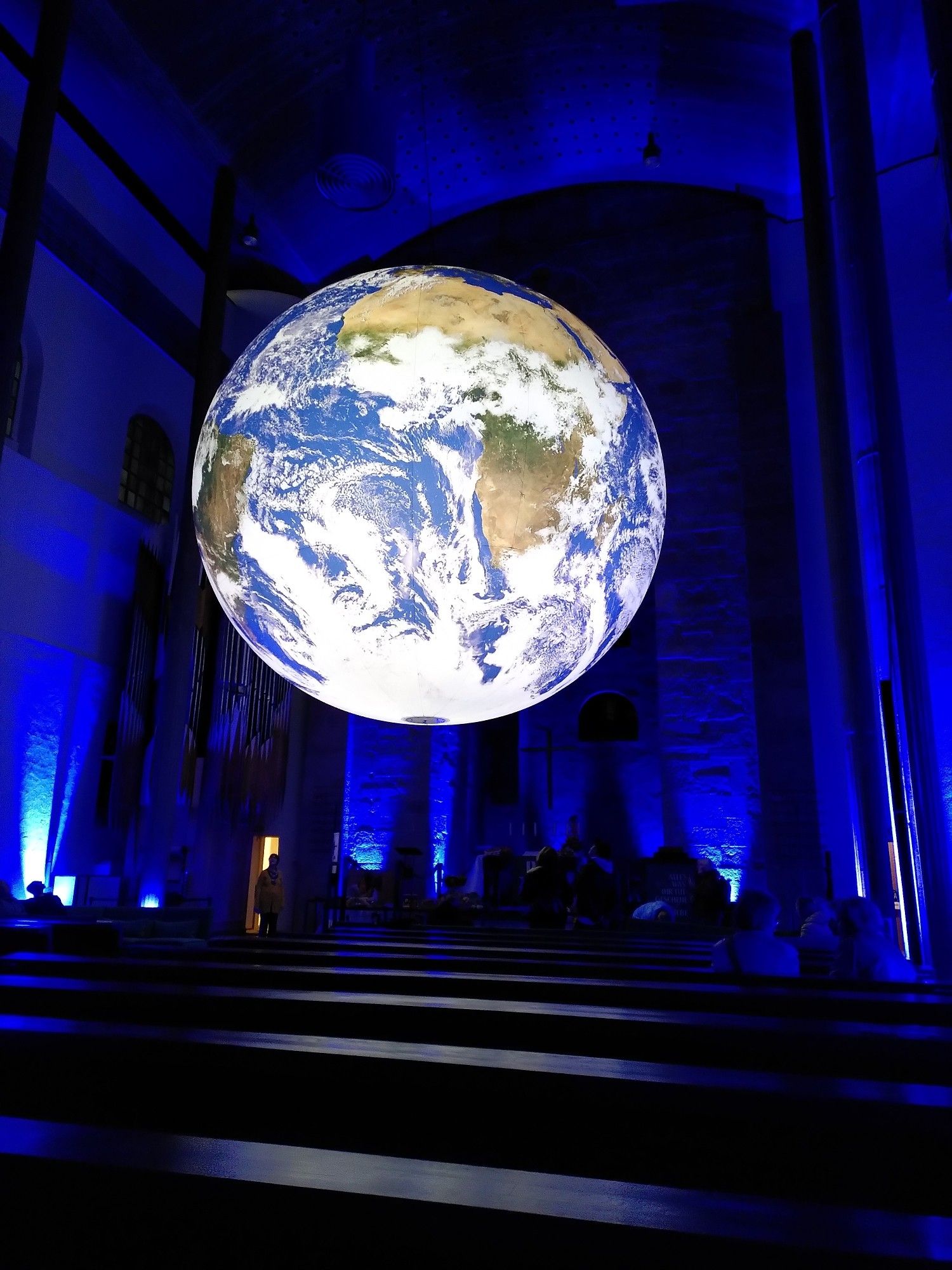 Blick von unten auf die von innen leuchtende Weltkugel. Zu sehen ist Afrika und ein Teil von Südamerika. Der Innenraum der Kirche ist drucken und daher nur zu erahnen.