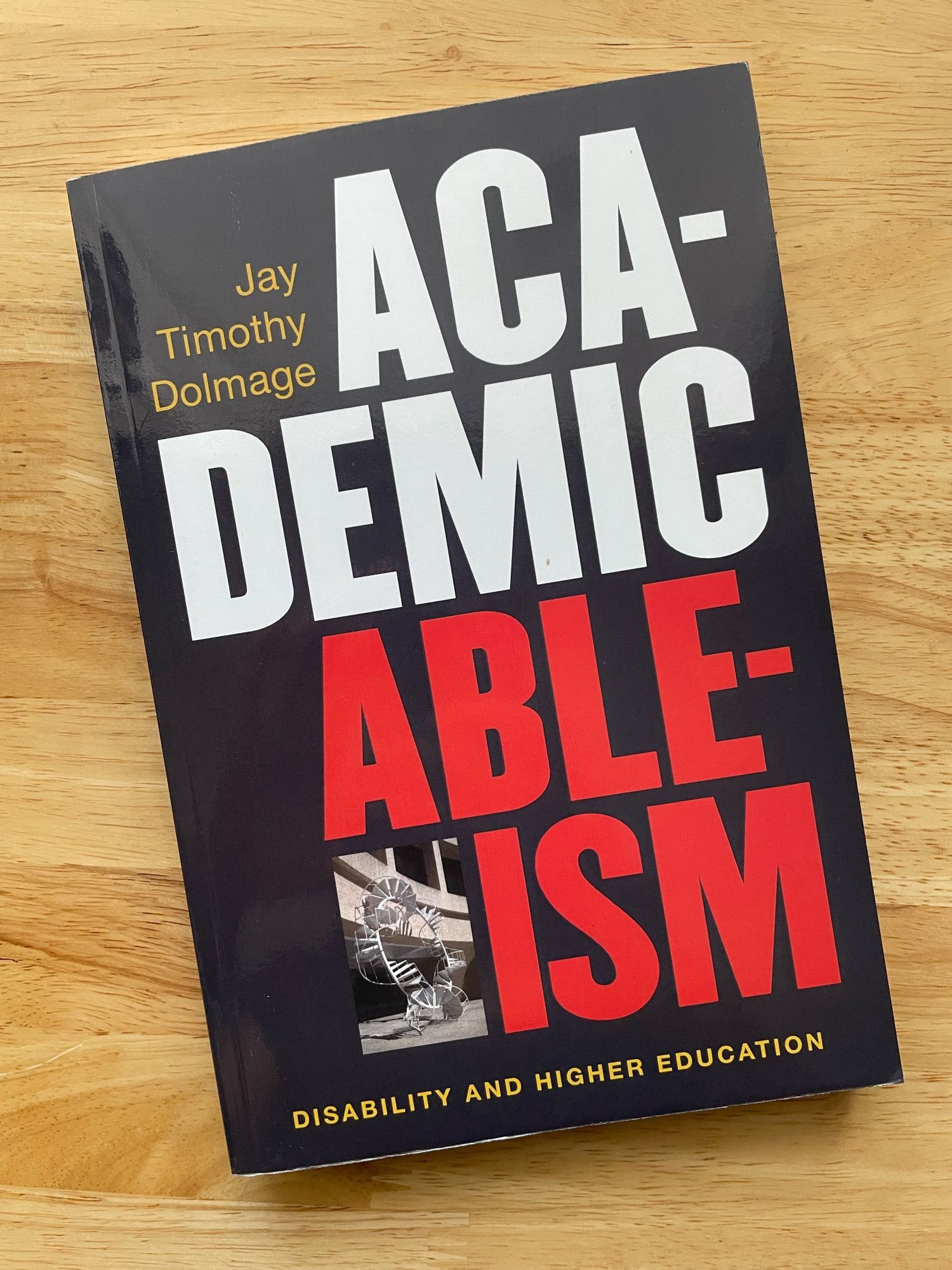 A book entitled, Academic Ableism: Disability and Higher Education, lays on a wooden desk.