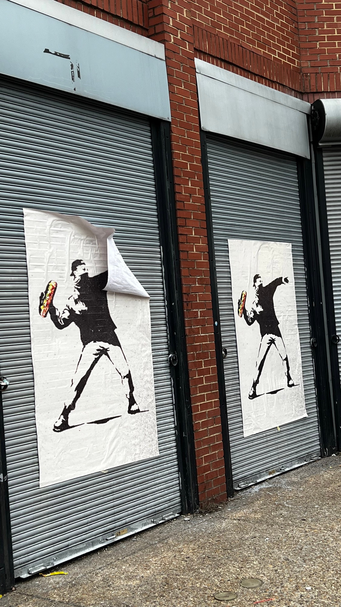 Posters on the street with a banksy style drawing of a man throwing a sub sandwich 