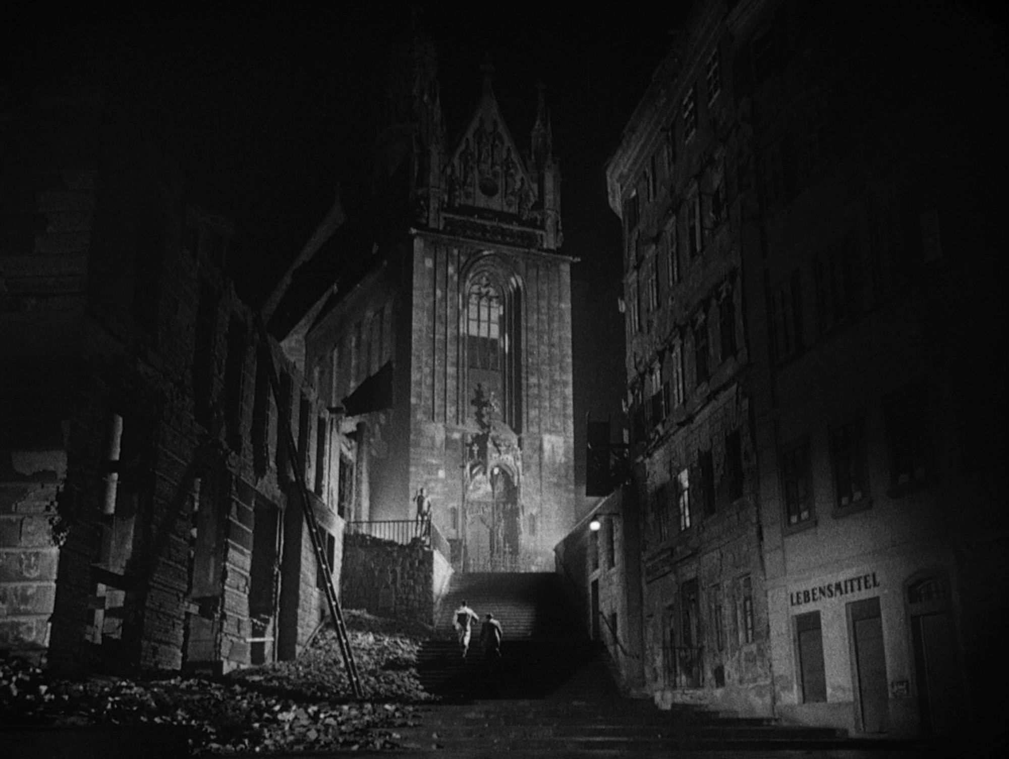 Black & white shot from the film "The third man", showing a scene from post-war Vienna: a church and a ruined building, at night.