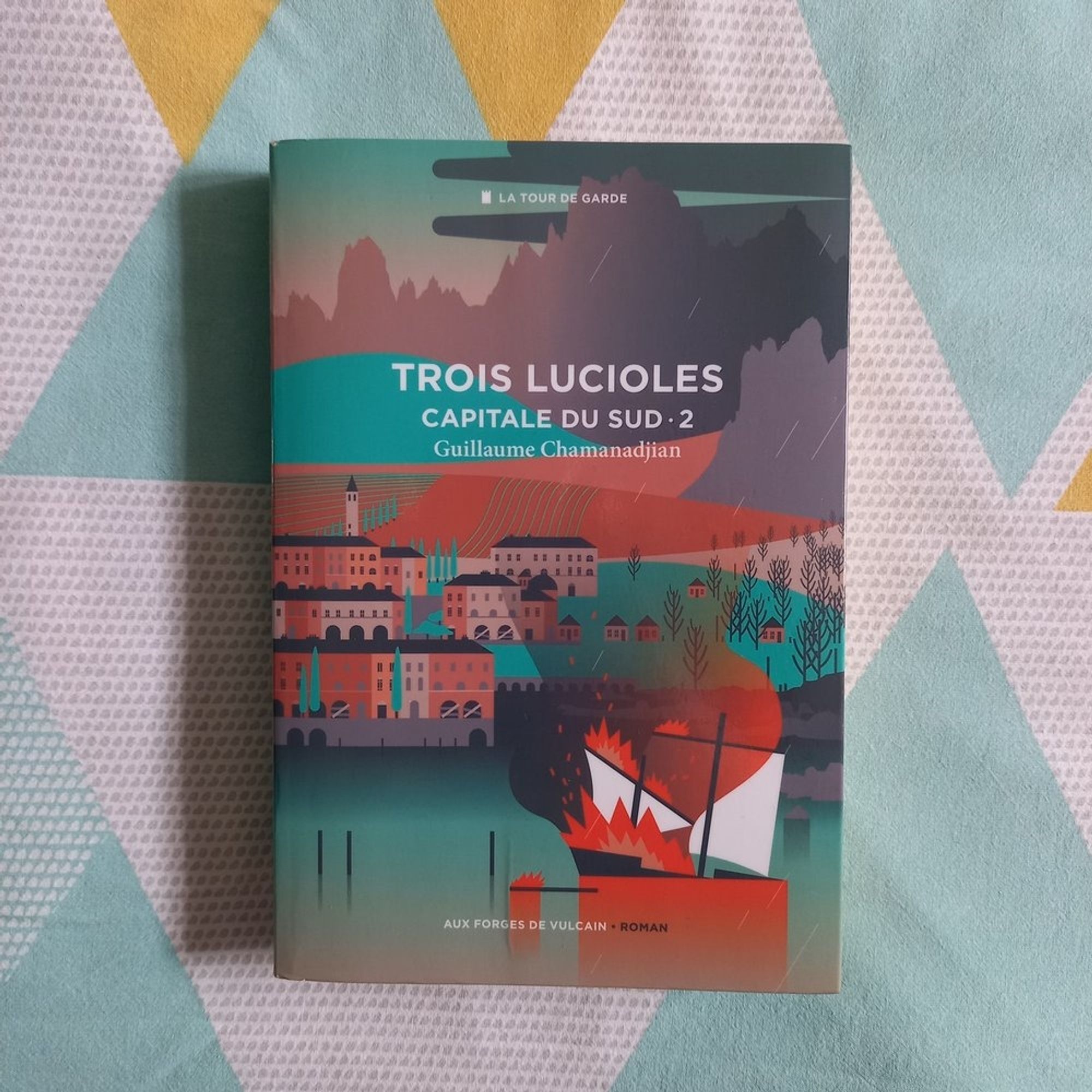 Trois lucioles, troisième tome du cycle de la Tour de garde et deuxième tome du sous-cycle Capital du Sud de Guillaume Chamanadjian (éditions Aux forges de Vulcain). La couverture montre une ville stylisée entourée de campagne, au bord d'un plan d'eau sur lequel brûle un bateau à voile