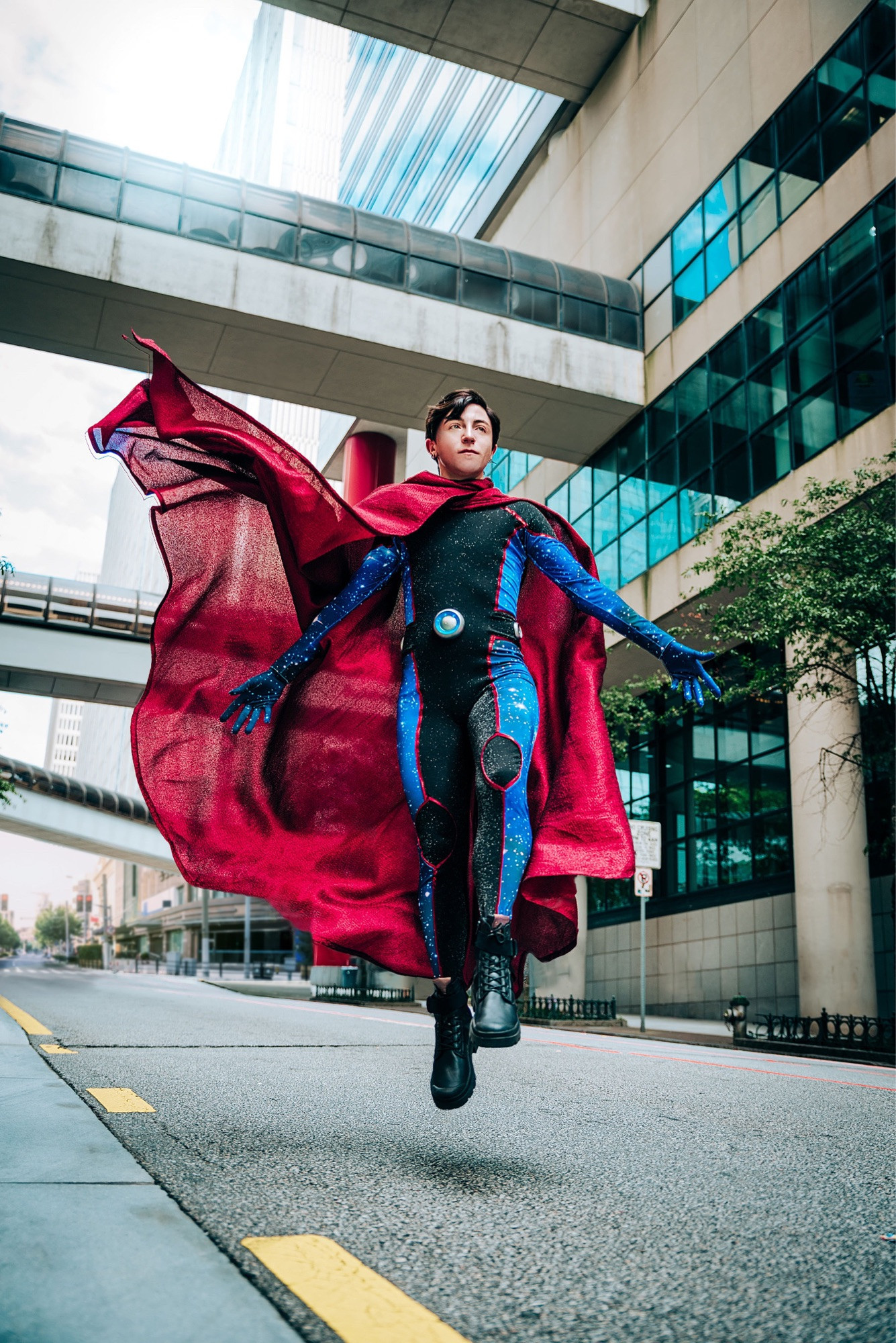 A Cosplayer dressed as Wiccan / Billy Kaplan from Marvel Comics Young Avenger floating in the air with his cape swirling around him