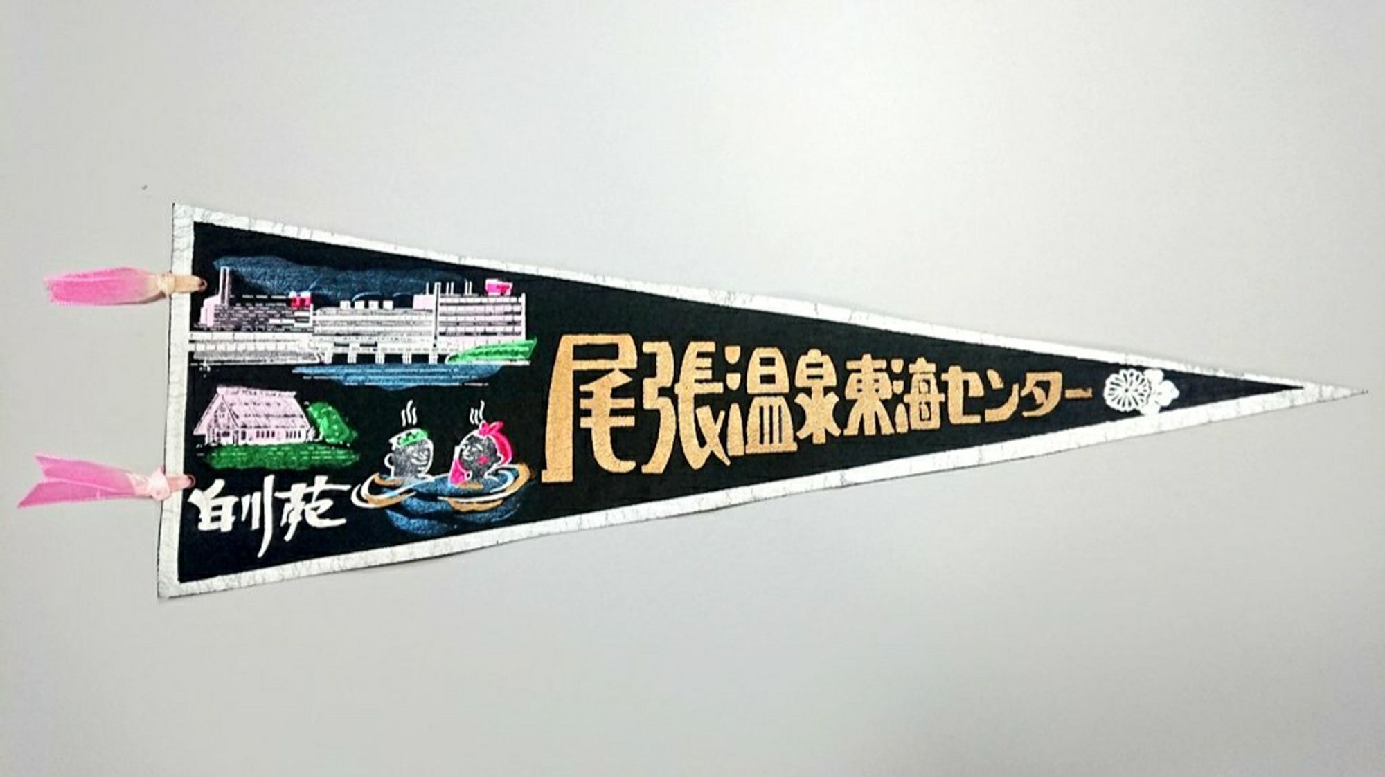 1, Owari Onsen pennant. Illustration printed on black cloth. Two pink ribbons are attached.