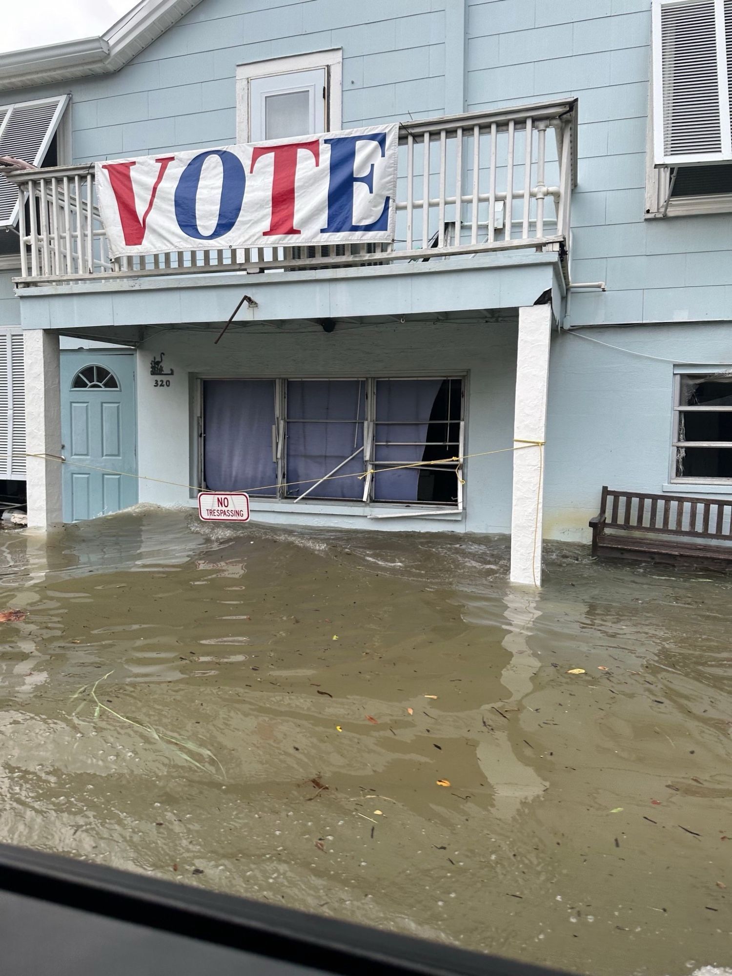 A flooded house with a giant banner on it that says vote