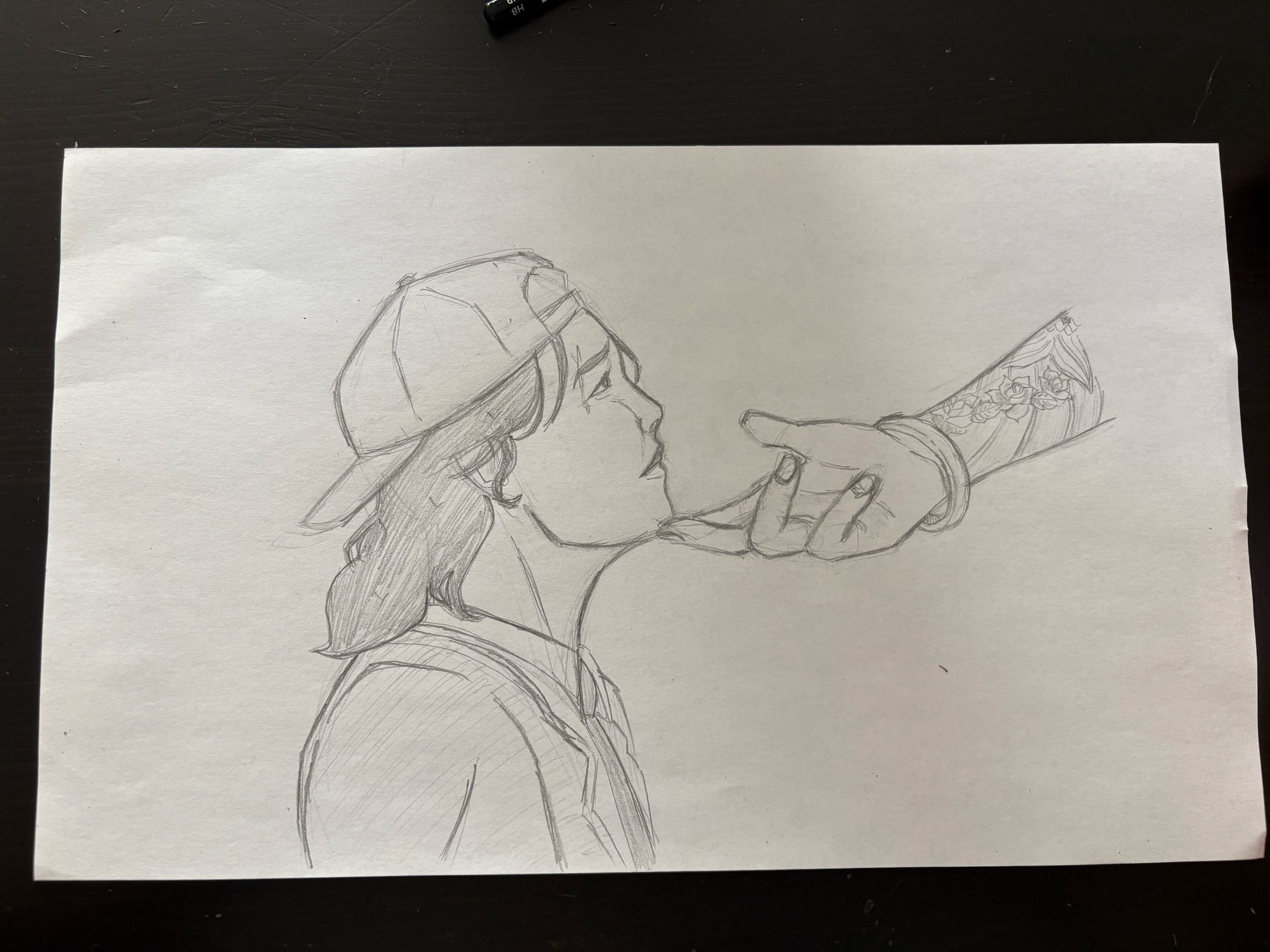 Pencil drawing of Avery looking up and Nico’s hand on her chin. Avery has medium length hair and a backwards baseball hat and a college uniform that consists of a suit and tie. Nico’s arm has a bracelet and tattoos and the hand is definitely drawn too big but please ignore that.