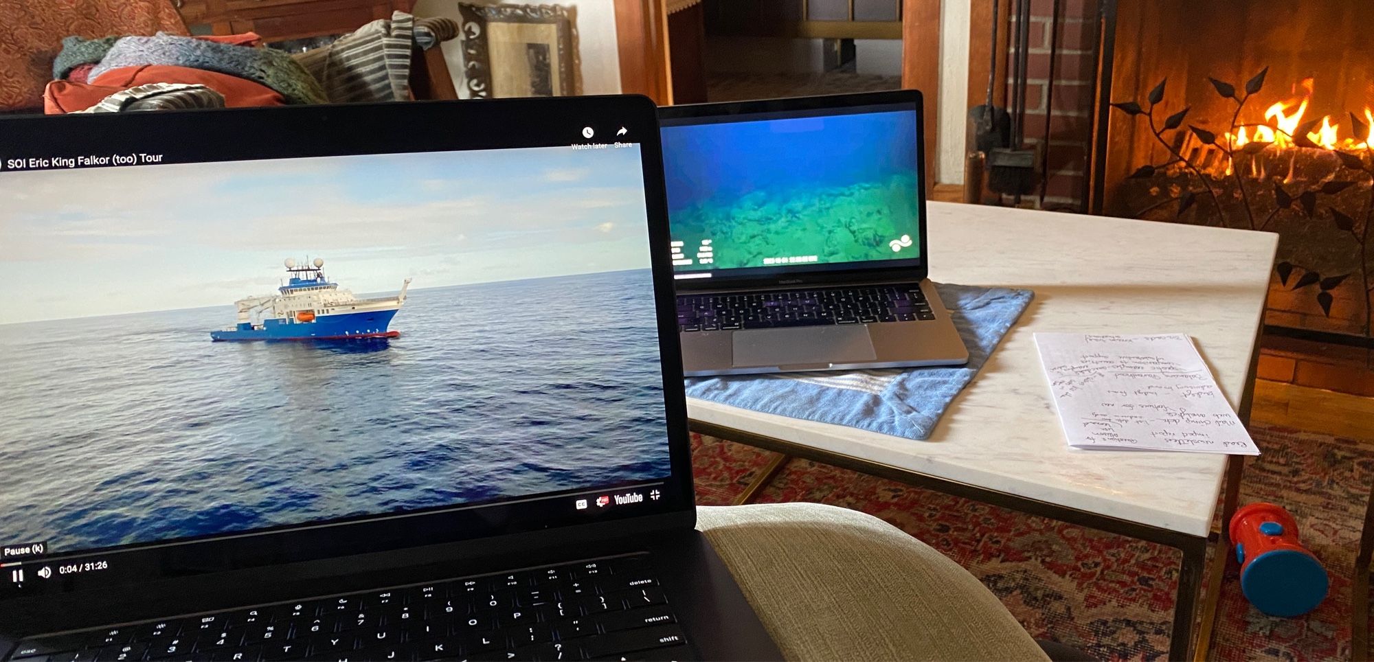 Two computer screens with ocean images in front of a fireplace