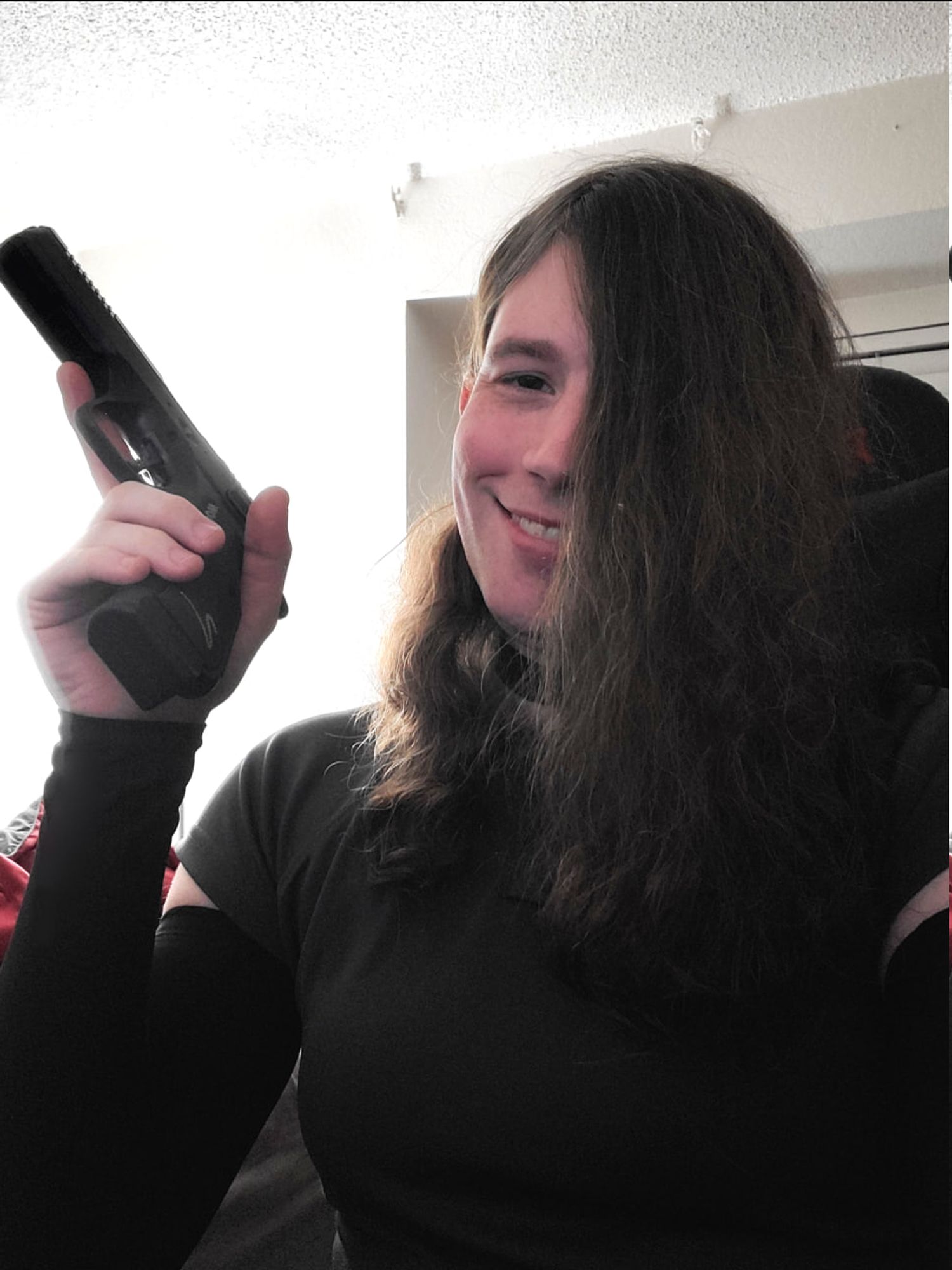 ellie in a grey polo, black, compression sleeves and a black choker, smiling while holding her very modified cz shadow 2 off to the side