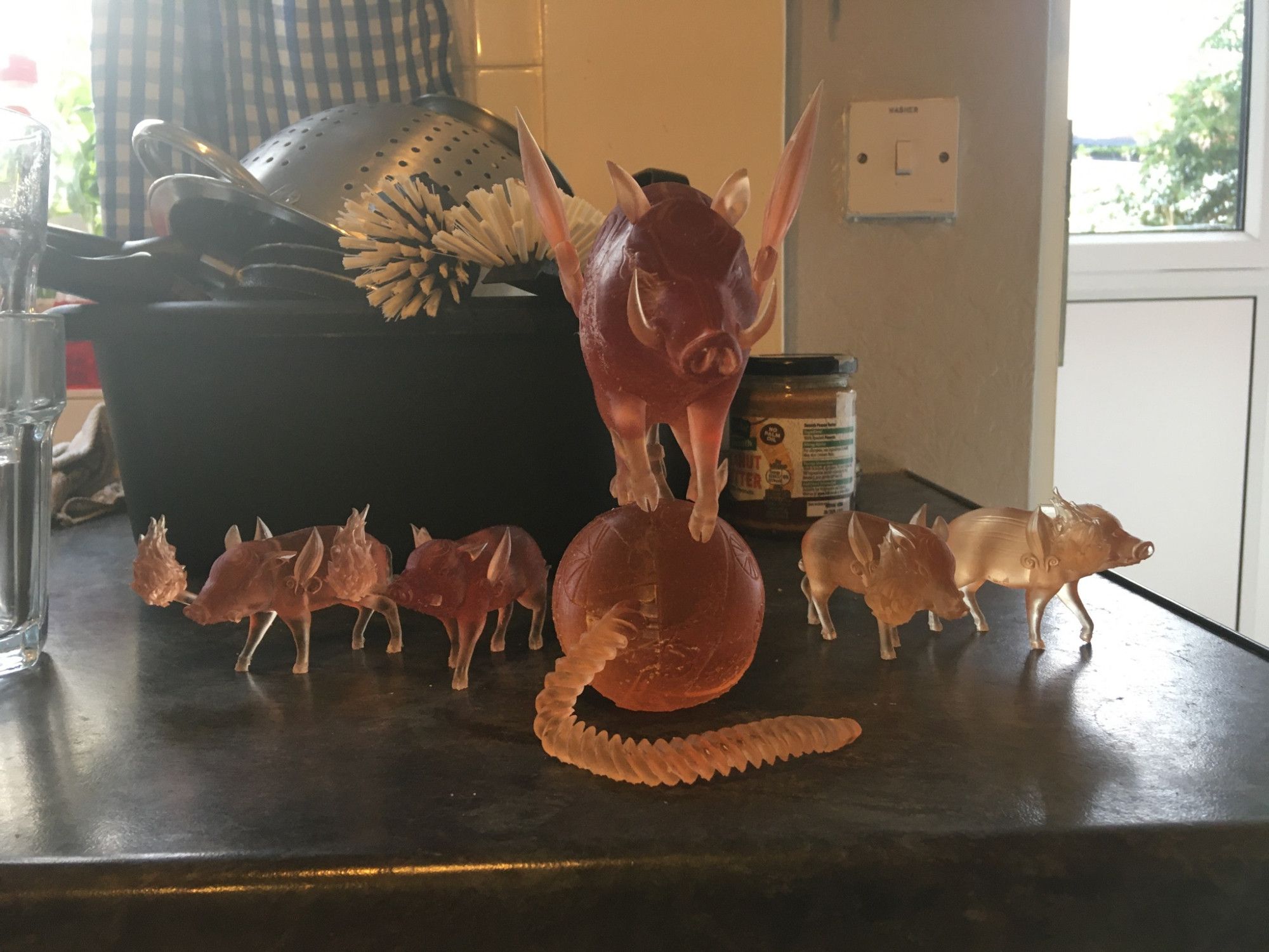 Photos of newly 3D printed models featuring a giant wild boar standing on a japanese cherry bomb and four piglets holding torches with fire. The prints are translucent orange.