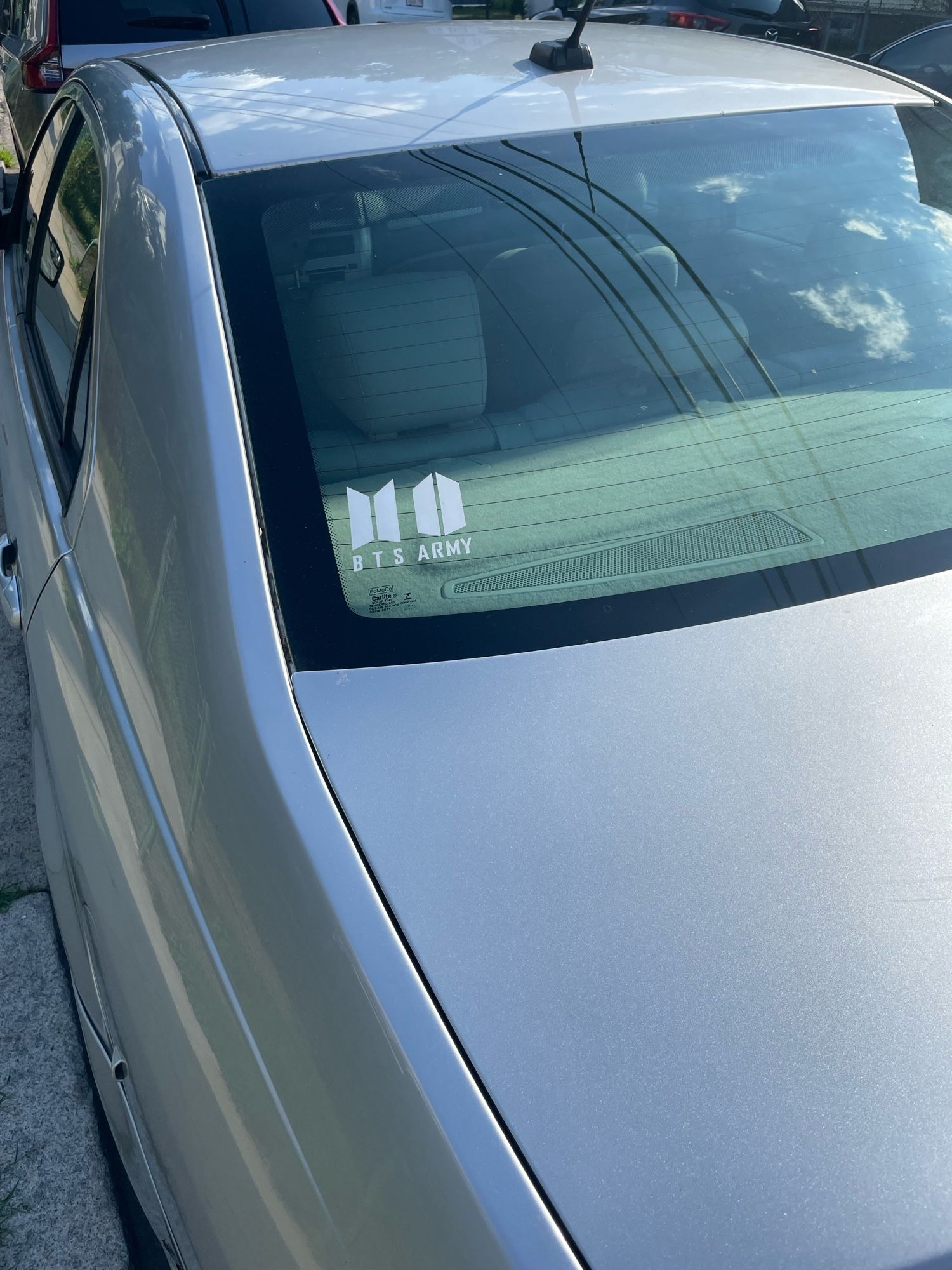 A silver Ford Fusion with white BTS Army stickers on the back window