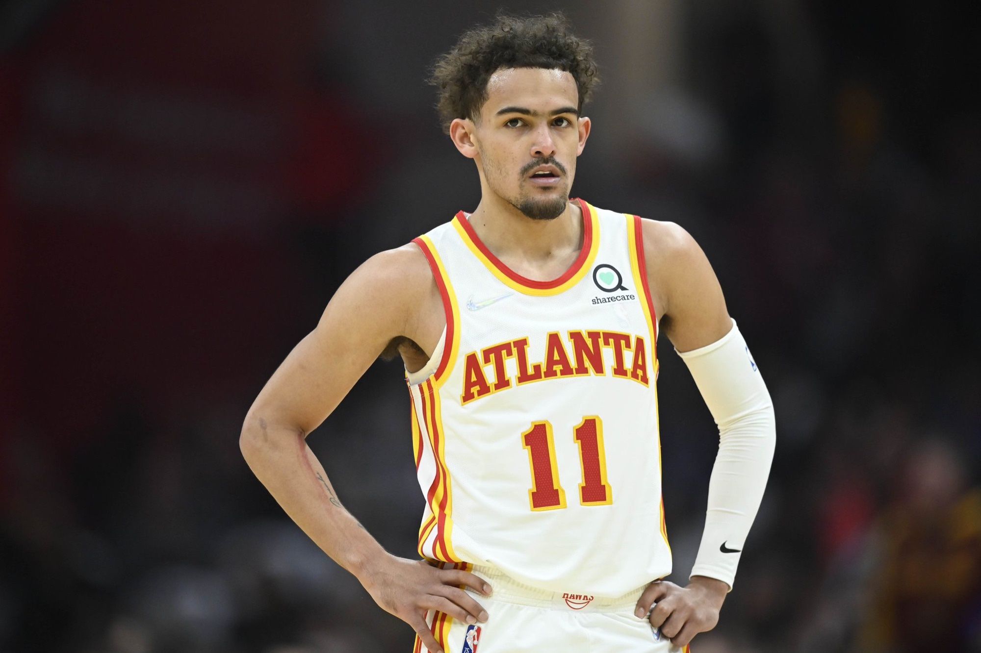 Trae Young stands on a basketball court with his hands on his hips