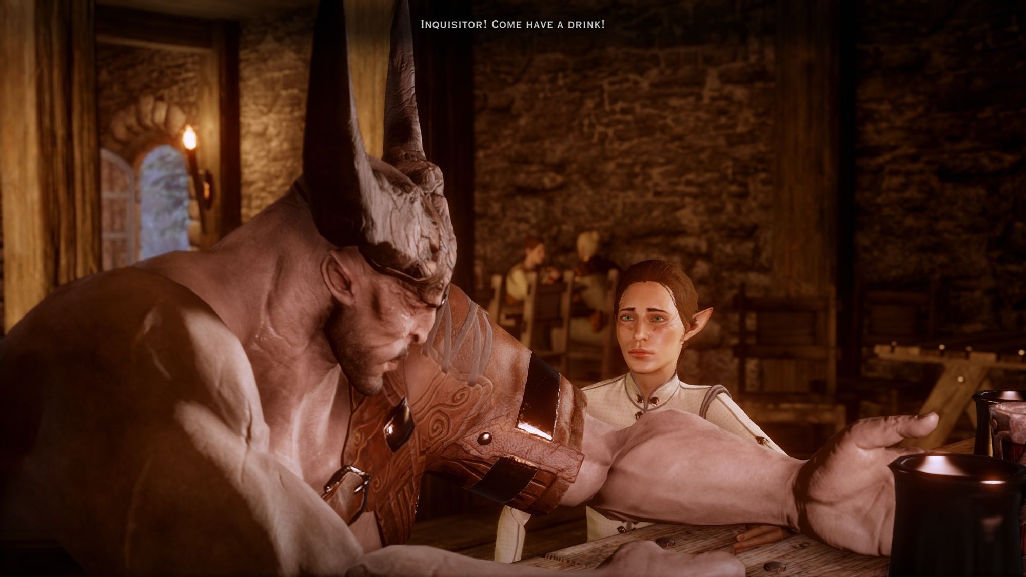 screenshot of dragon age inquisition in the tavern at skyhold. my character is sitting with iron bull at the bar table, hes sideways facing my character with his arm out over the table near a large alcoholic drink. my elf is behind his arm and looks very tiny because iron bull is a huge half bull creature